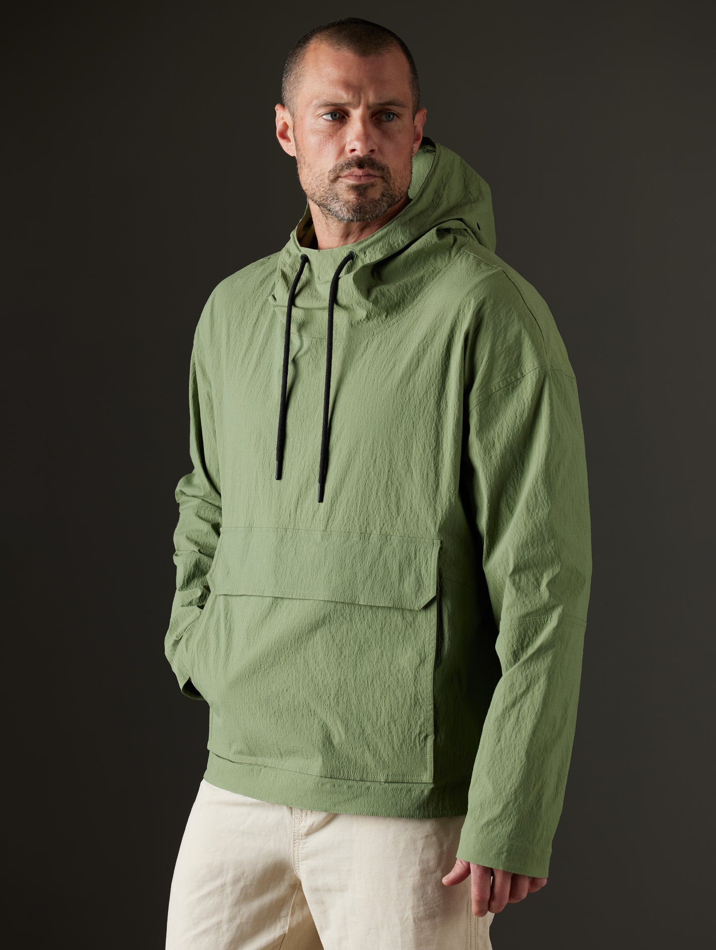 Front 3/4 body view of man wearing Harrier Anorak in Mineral Green from AETHER Apparel.