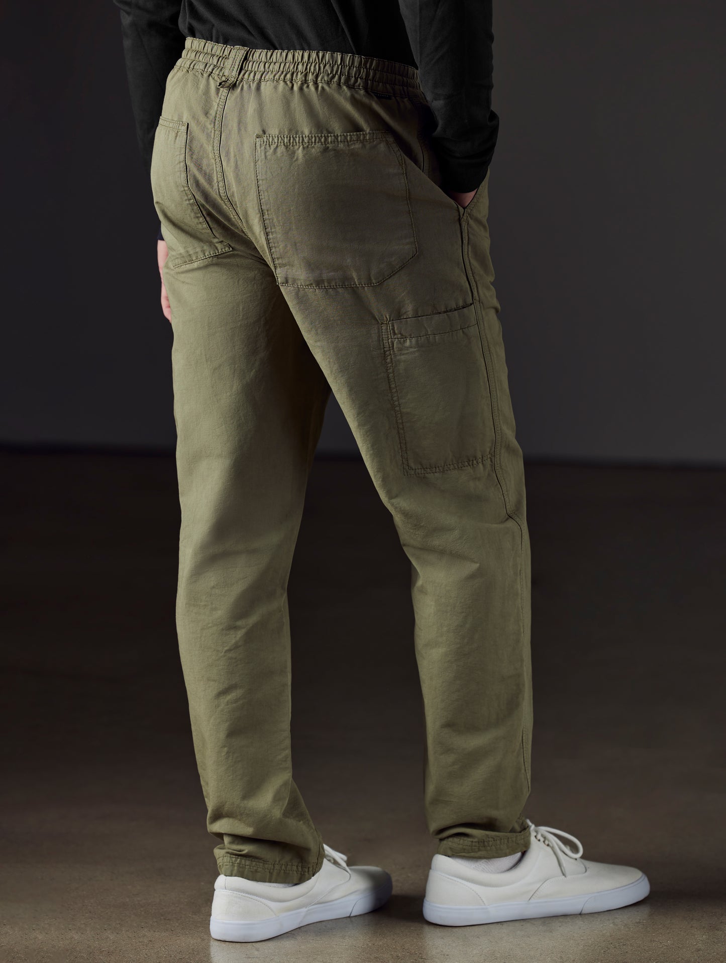Rear 3/4 lower body view of man wearing Highland Drawstring Pant in Fern Green from AETHER Apparel.