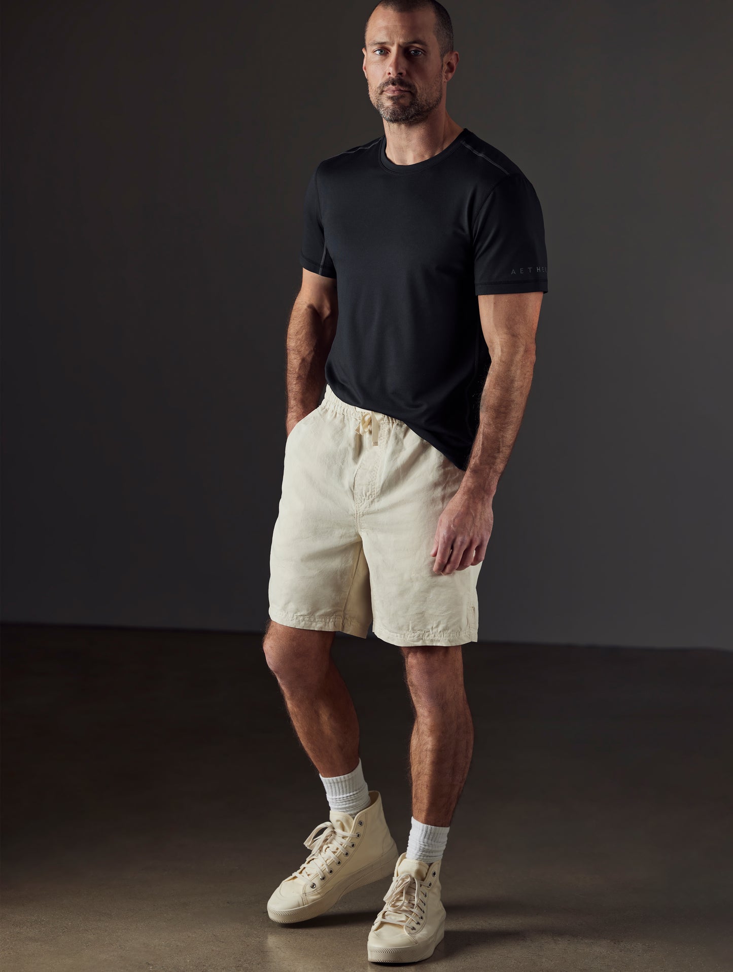 Front 3/4 full-body view of man wearing Highland Drawstring Short in Bone white from AETHER Apparel.
