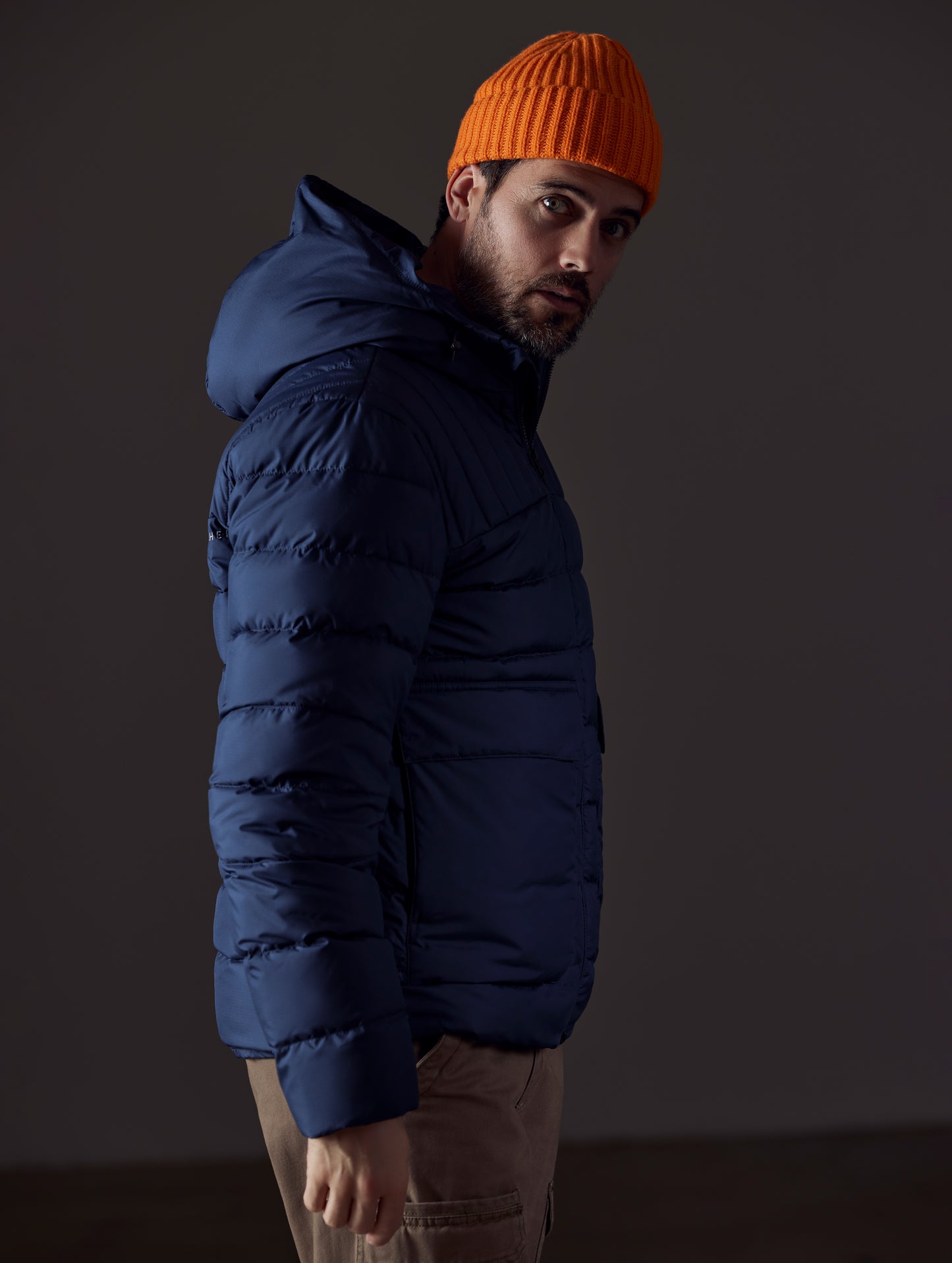 Side profile body view of man wearing Hudson Down Jacket in Total Eclipse dark blue from AETHER Apparel.