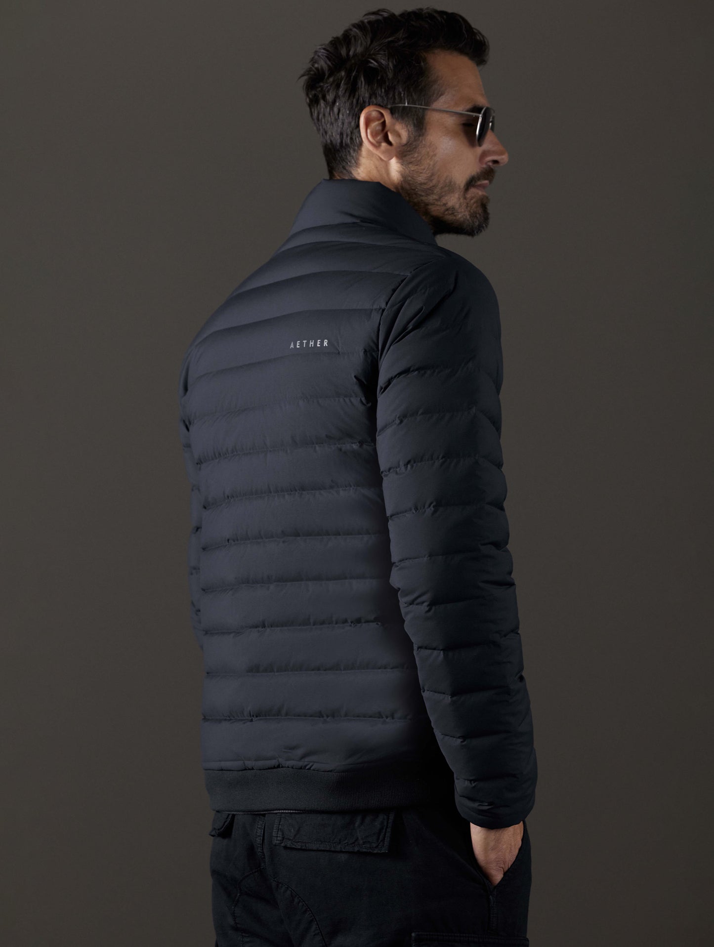 Rear 3/4 body view of man wearing Launch Full-Zip Jacket NH in Onyx Black from AETHER Apparel.