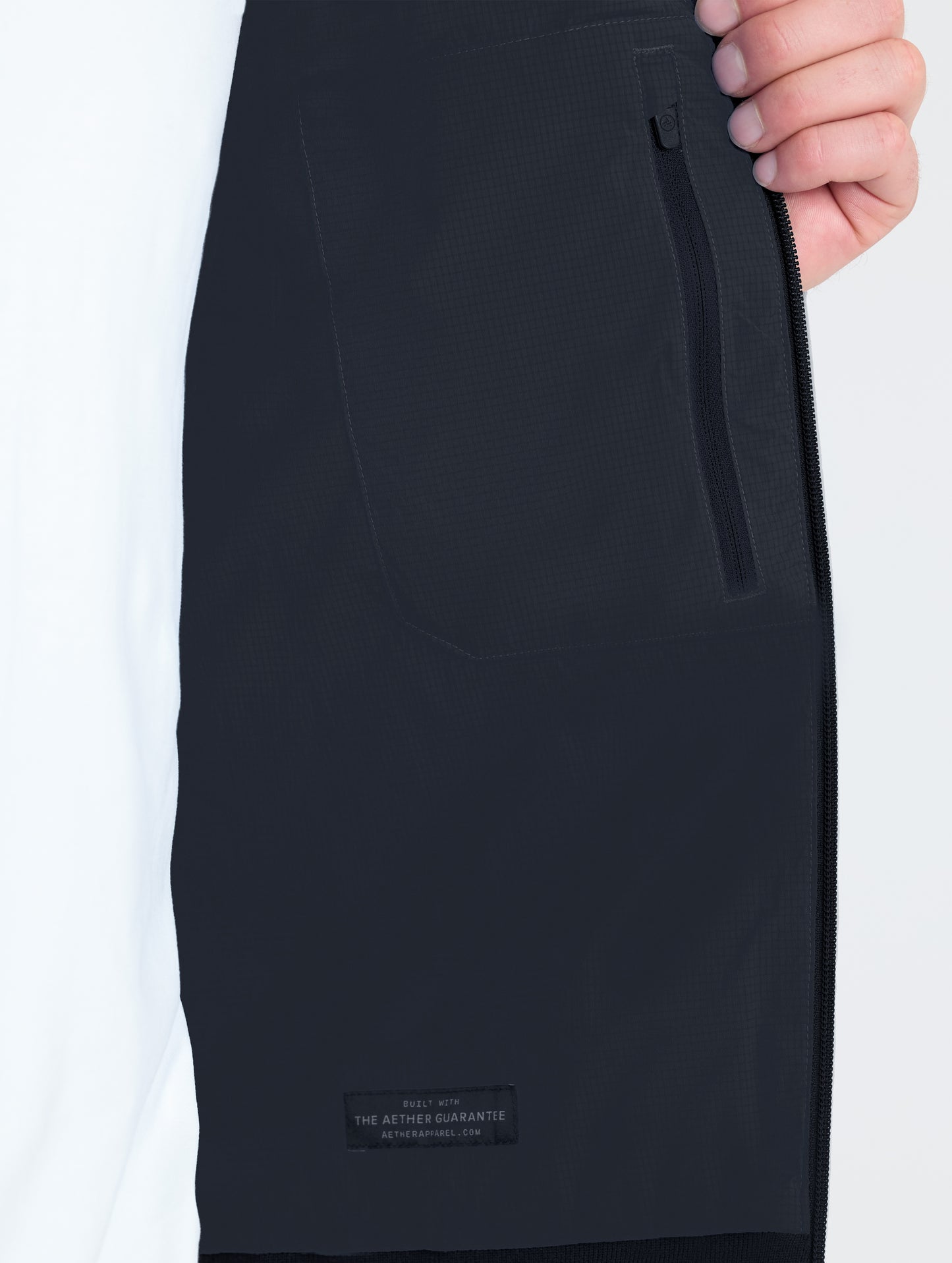 Closeup view of wearer's interior left zipped pocket of Launch Jacket in Onyx Black from AETHER Apparel.