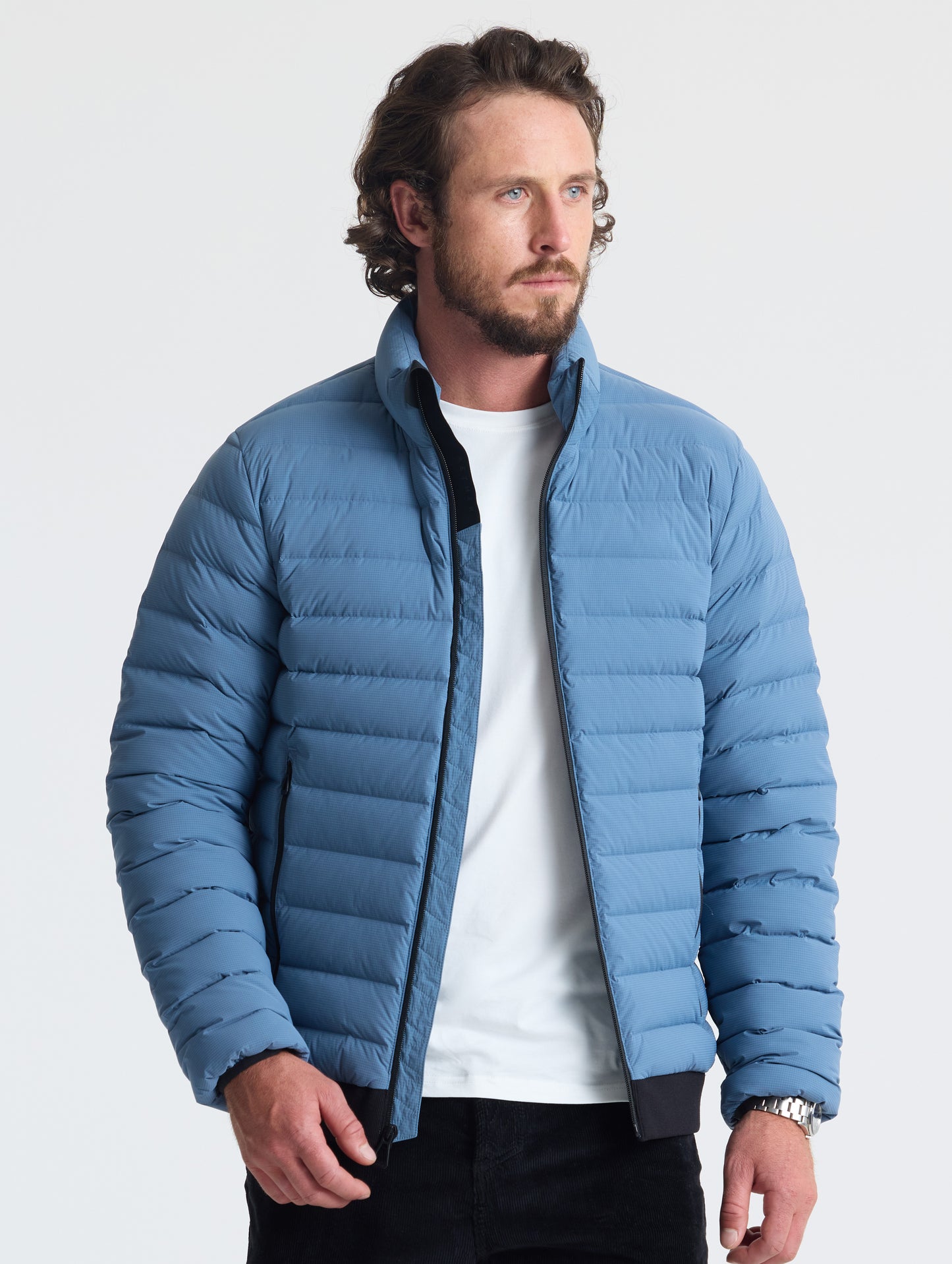 Front view of man wearing unzipped Prospect Packable Down Jacket in Portal Blue from AETHER Apparel.