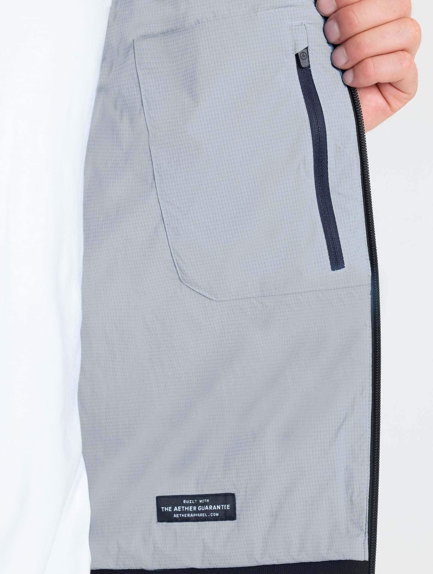 Closeup view of wearer's interior left zipped pocket of Launch Jacket in Sky Grey from AETHER Apparel.
