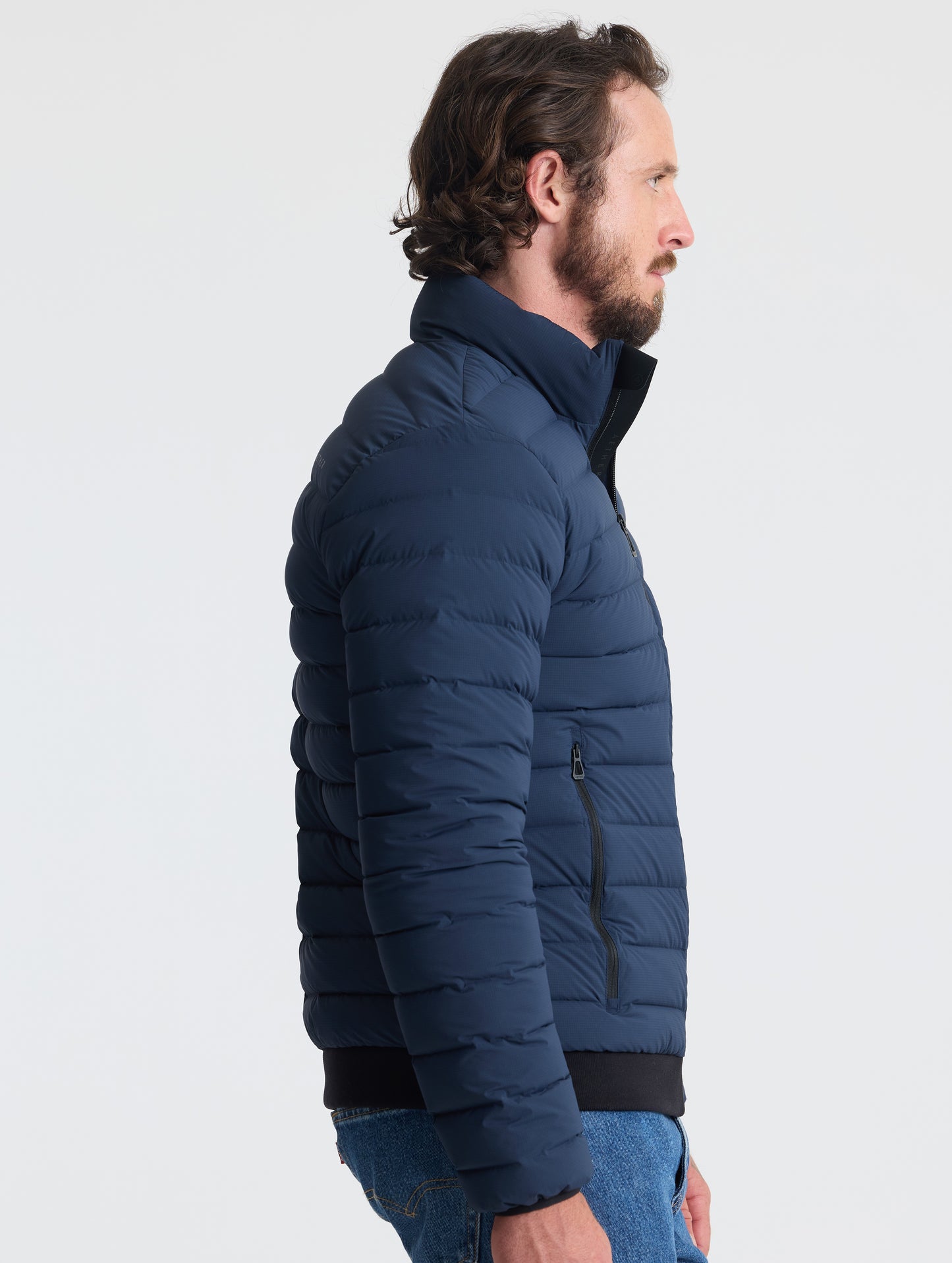 Right profile view of man wearing Launch Jacket in Total Eclipse dark blue from AETHER Apparel.