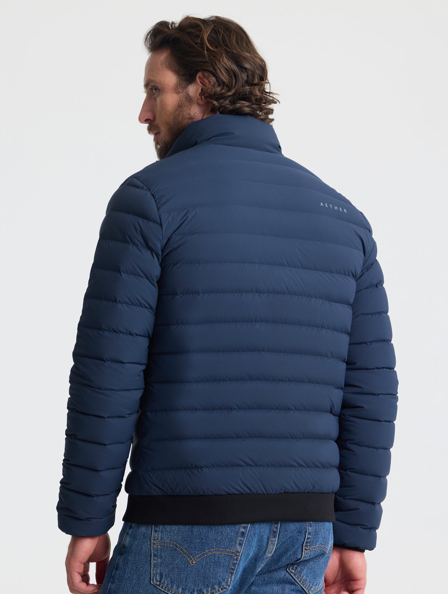 Rear view of man wearing Launch Jacket in Total Eclipse dark blue from AETHER Apparel.