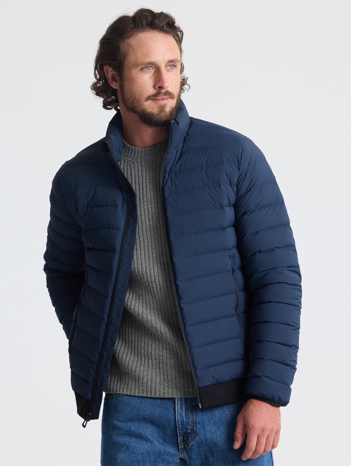 Front view of man wearing unzipped Launch Jacket in Total Eclipse dark blue from AETHER Apparel.