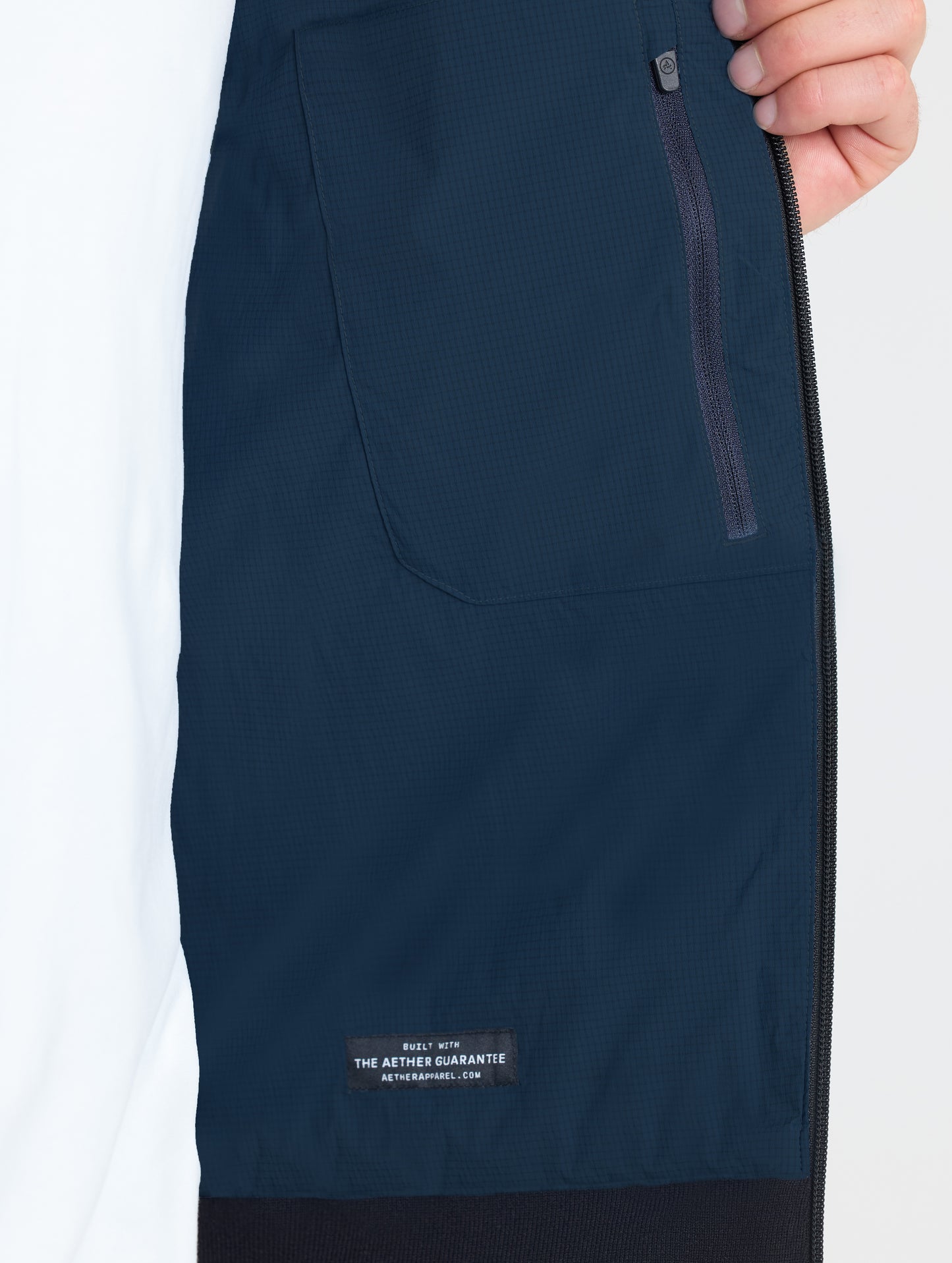 Closeup view of interior left zipped pocket of Launch Jacket in Total Eclipse dark blue from AETHER Apparel.
