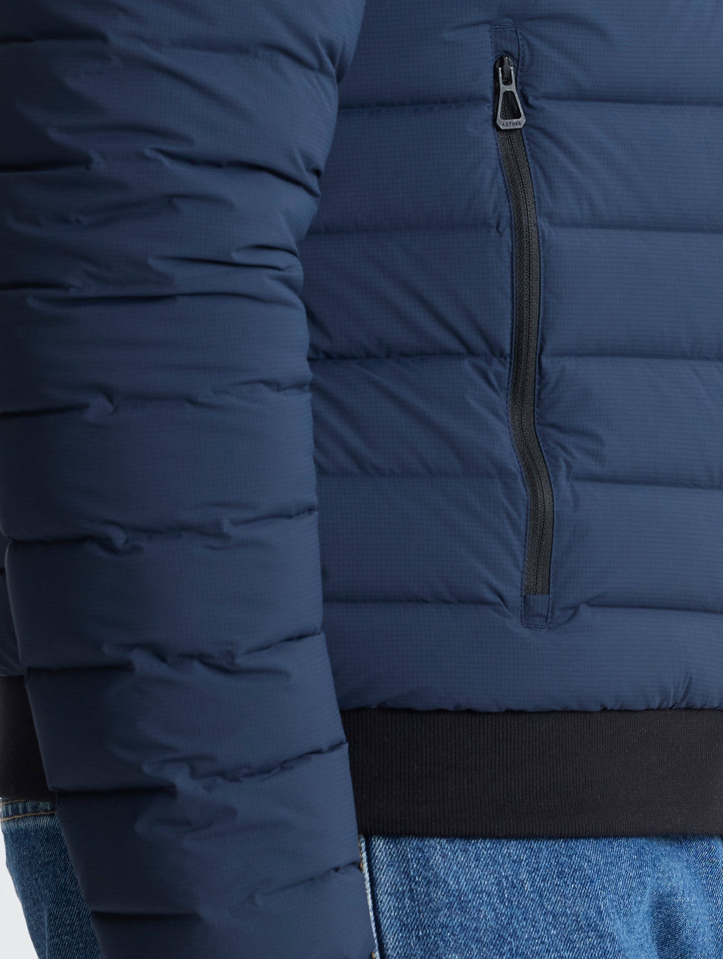 Closeup view of wearer's right zipped hand pocket of Launch Jacket in Total Eclipse dark blue from AETHER Apparel.