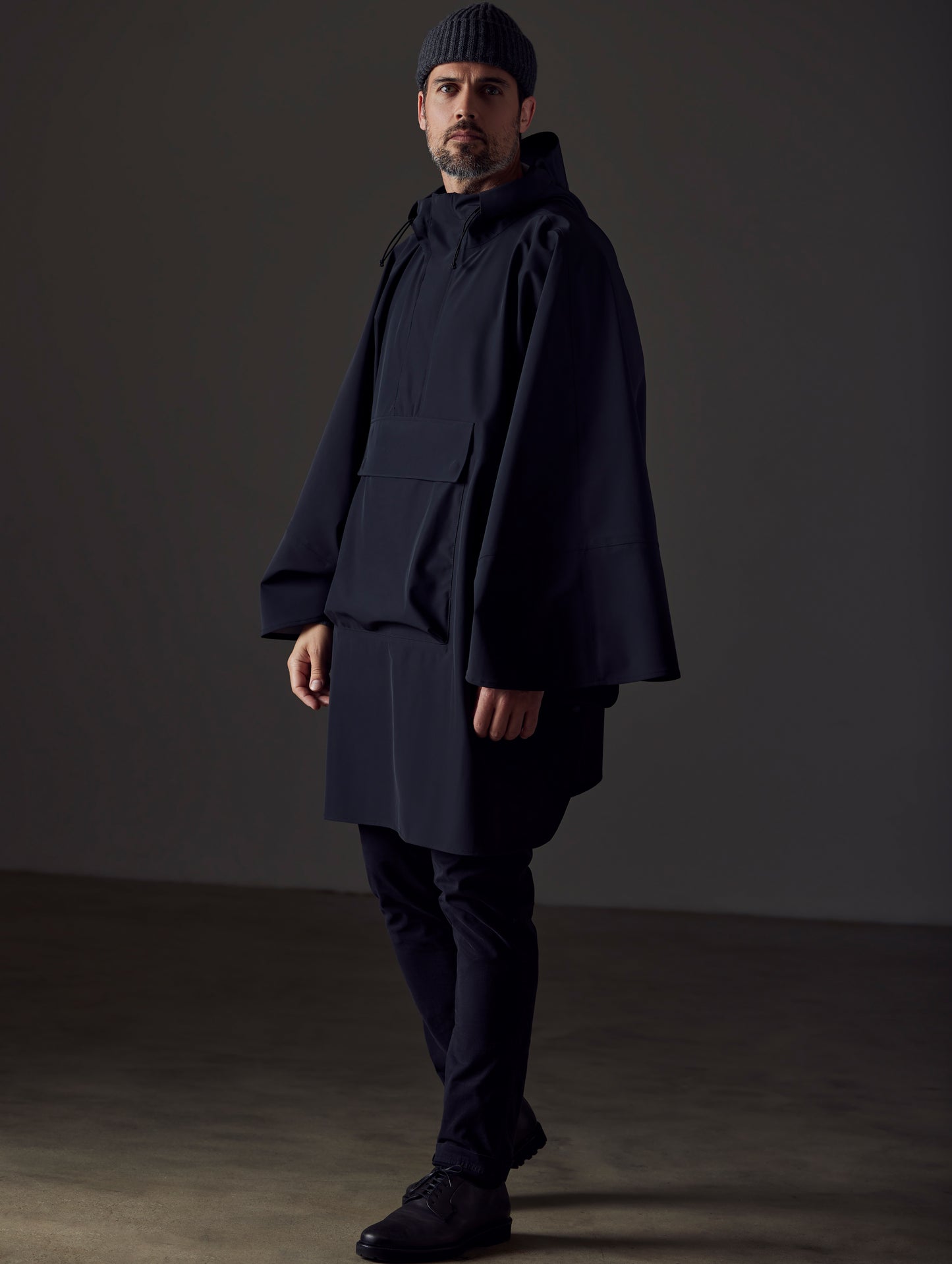 Full-body view of man wearing the Line Poncho in Onyx Black from AETHER Apparel.