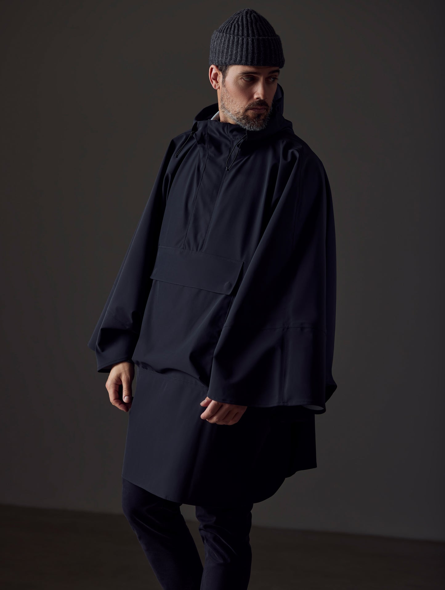 Front right-angled view of man wearing the Line Poncho in Onyx Black from AETHER Apparel.