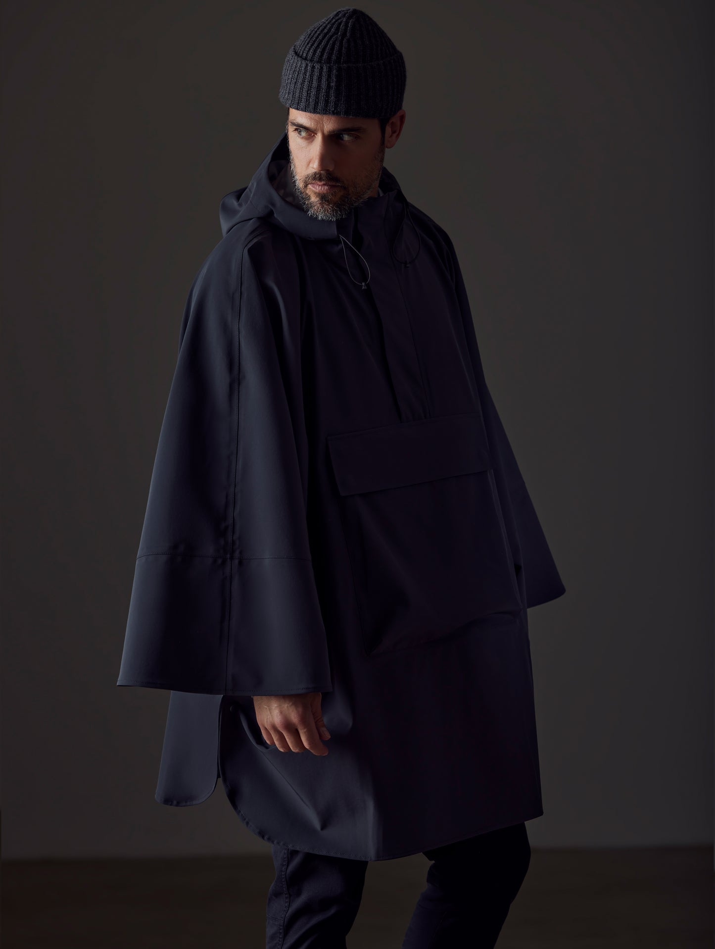 Front left-angled view of man wearing the Line Poncho in Onyx Black from AETHER Apparel.