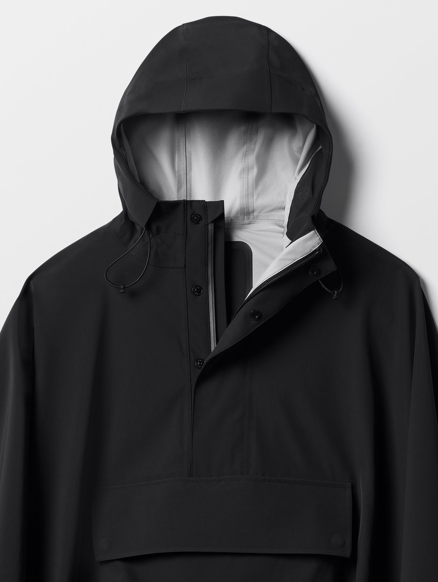 Closeup detailed view of the three-piece hood and quarter-length center-front zipper on the Line Poncho in Onyx Black from AETHER Apparel.