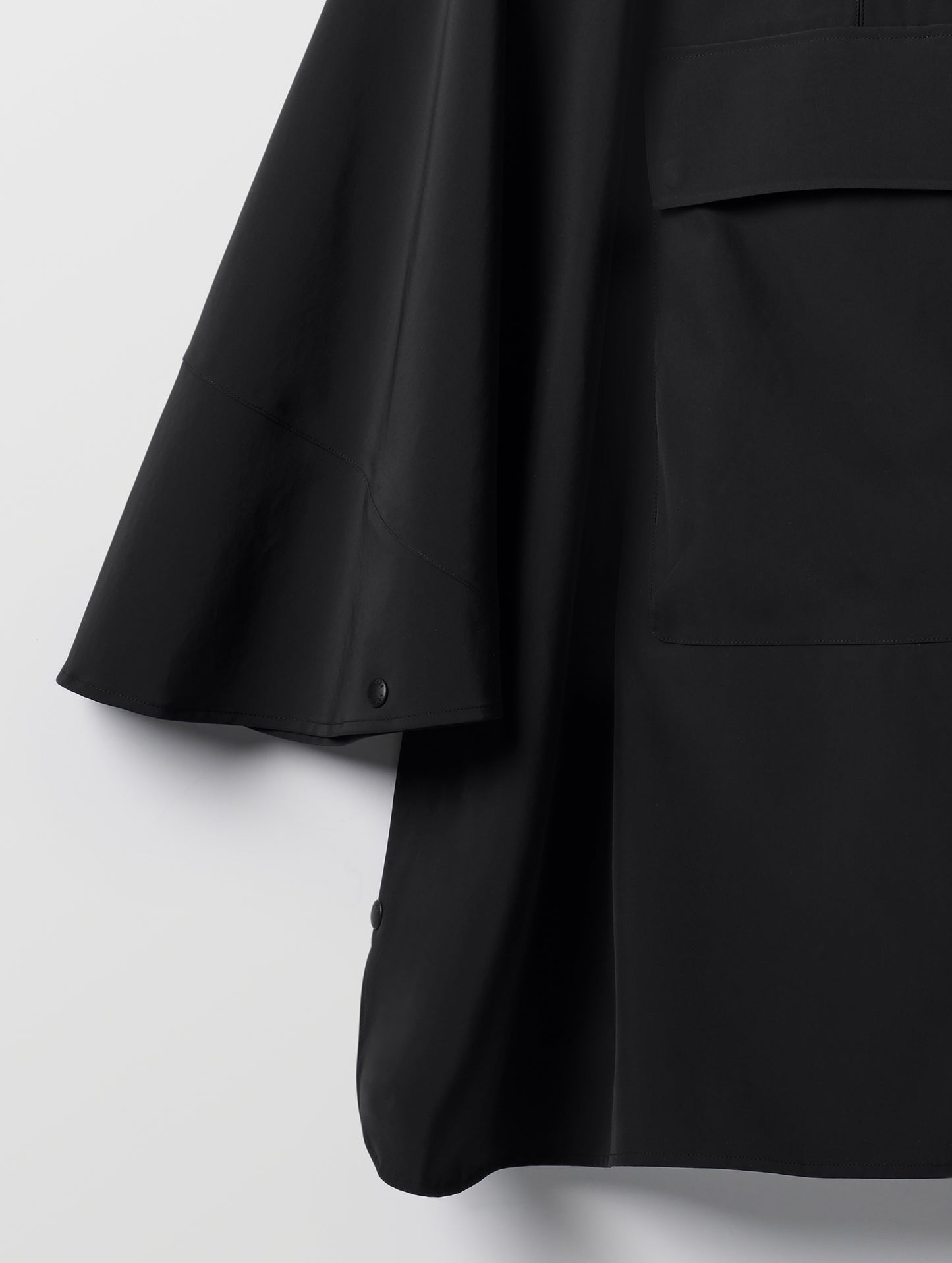 Closeup detailed view of the sleeve and bottom corner of the Line Poncho in Onyx Black from AETHER Apparel.