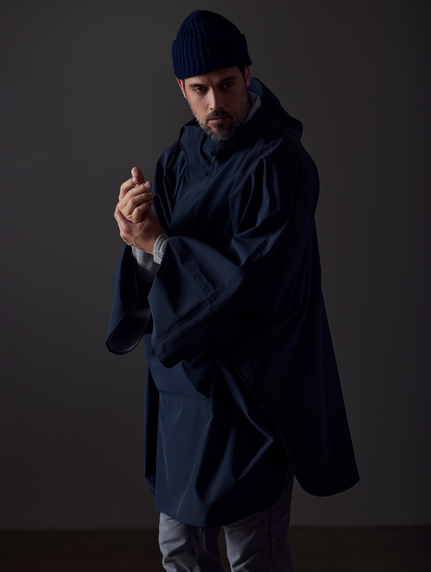 Front angled view of man wearing the Line Poncho in Total Eclipse dark blue from AETHER Apparel.
