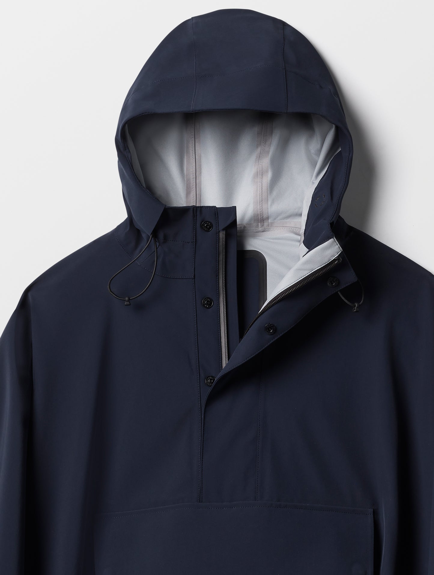 Closeup detailed view of the three-piece hood and quarter-length center-front zipper on the Line Poncho in Total Eclipse dark blue from AETHER Apparel.
