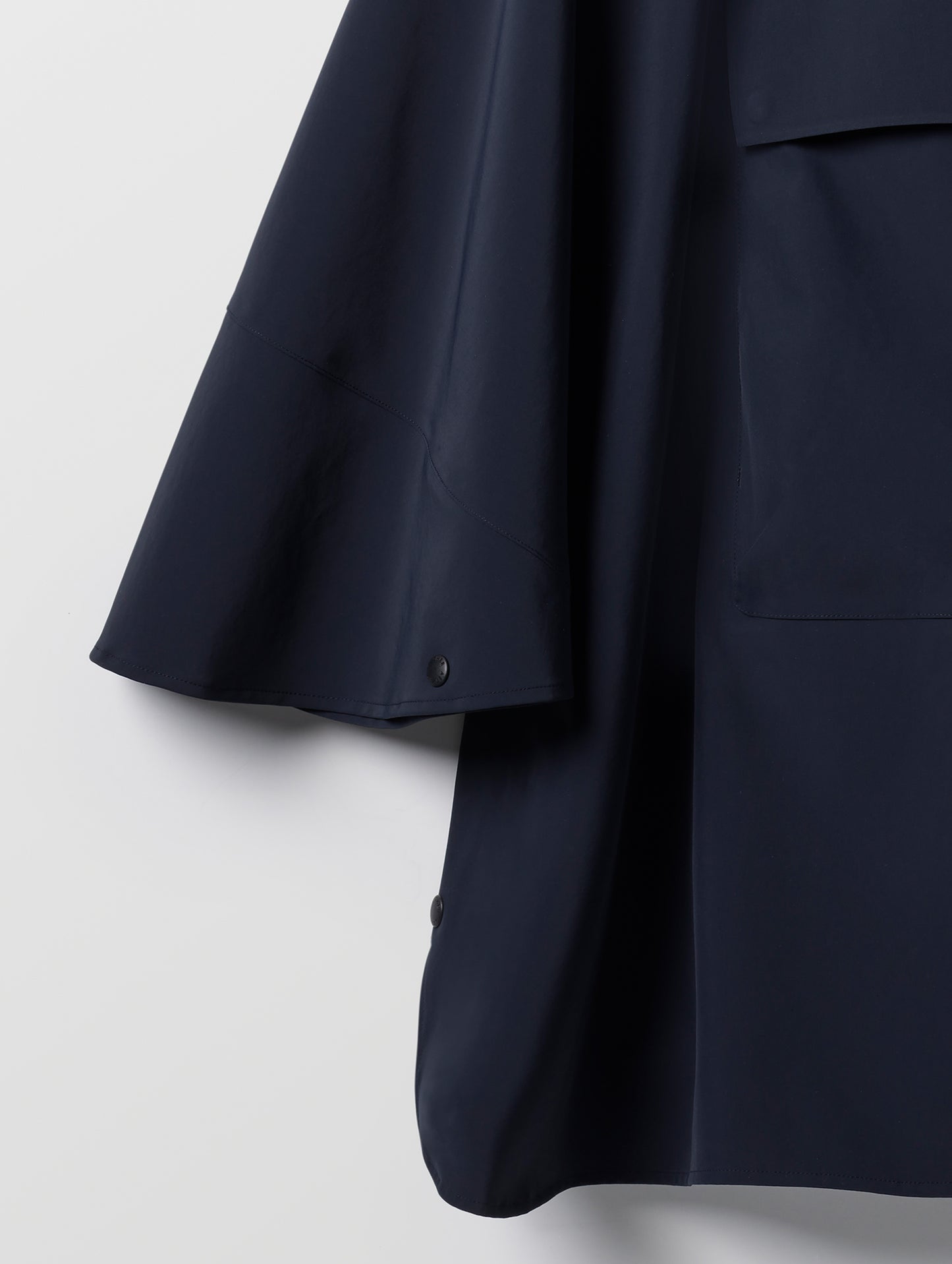 Closeup detailed view of the sleeve and bottom corner of the Line Poncho in Total Eclipse dark blue from AETHER Apparel.