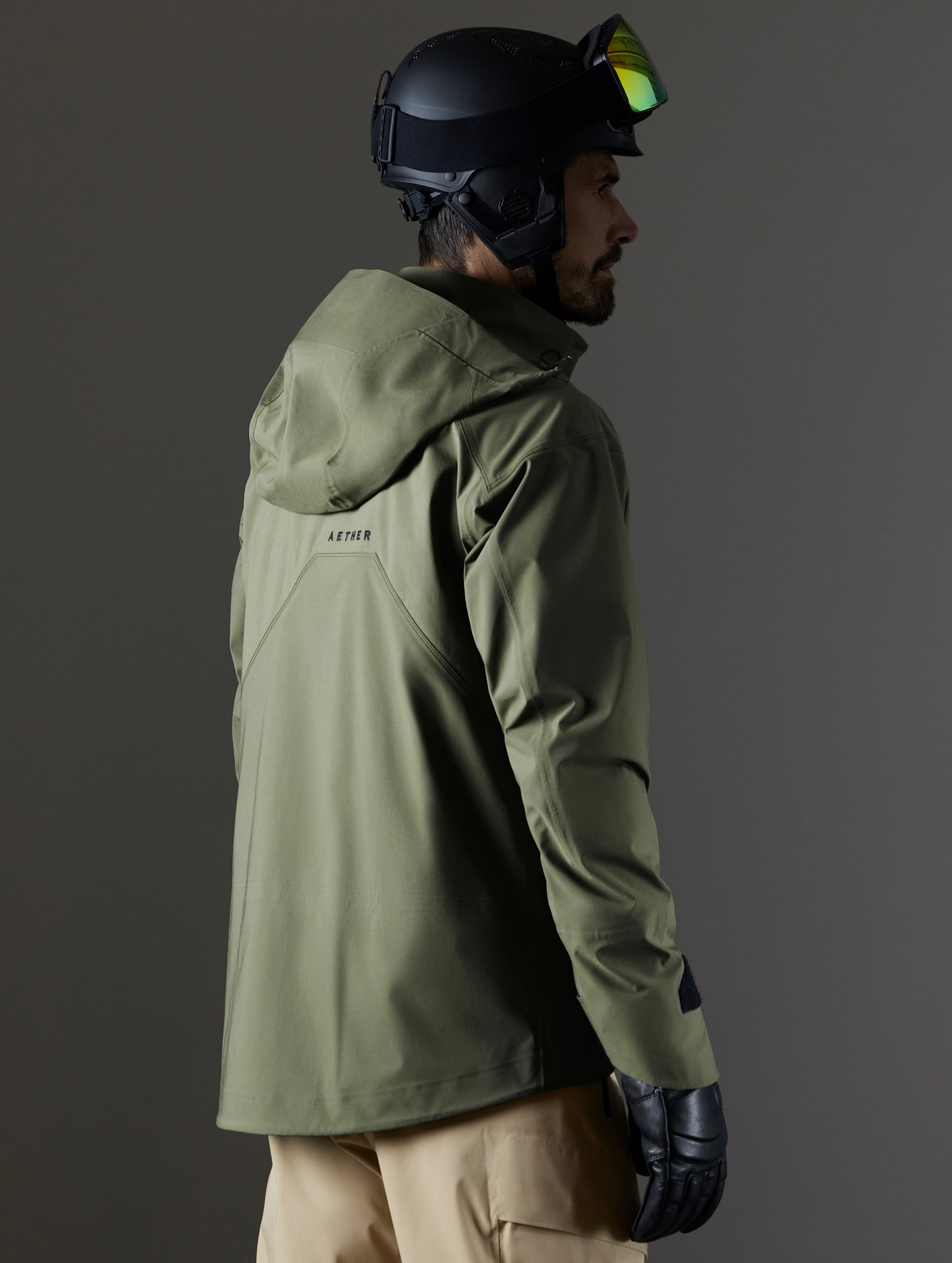 Rear 3/4 body view of man wearing Maverick Snow-Shell Jacket in Fern Green from AETHER Apparel.