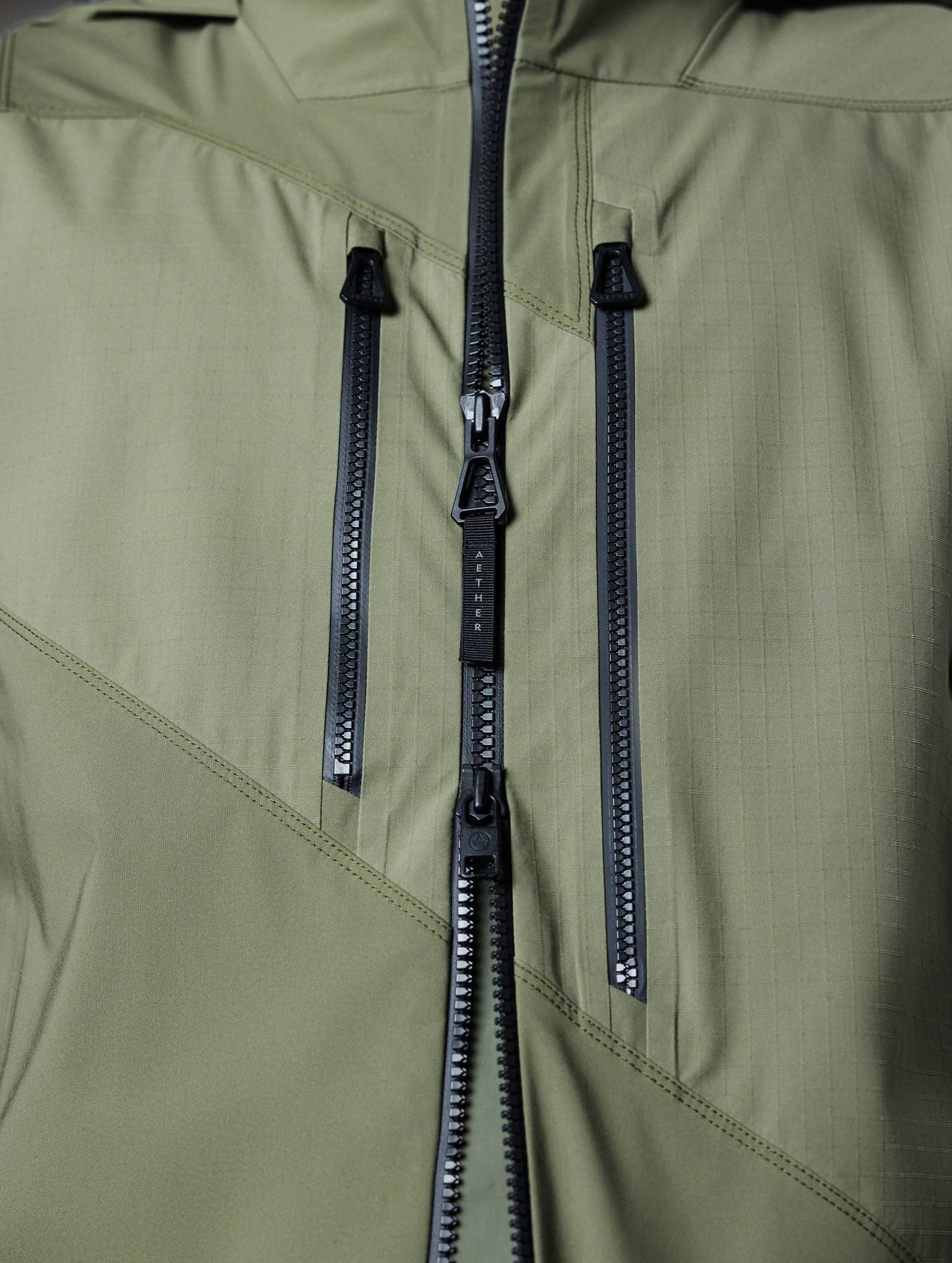 Closeup detailed view of the AquaGuard zipper-secured chest pockets and weatherproof two-way main center-front zipper of the Maverick Snow-Shell Jacket in Fern Green from AETHER Apparel.
