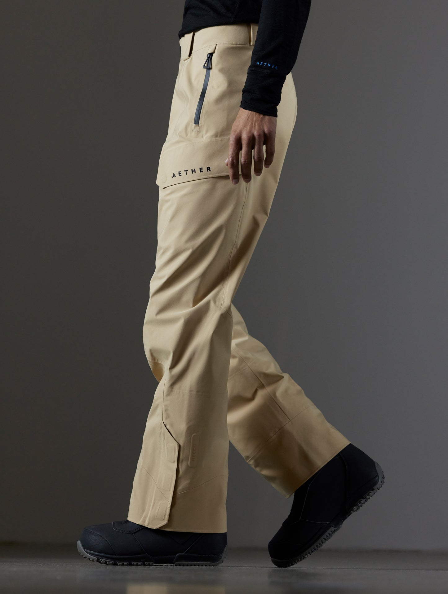 Side profile lower body view of man wearing Maverick Snow-Shell Pant in Desert Tan from AETHER Apparel.