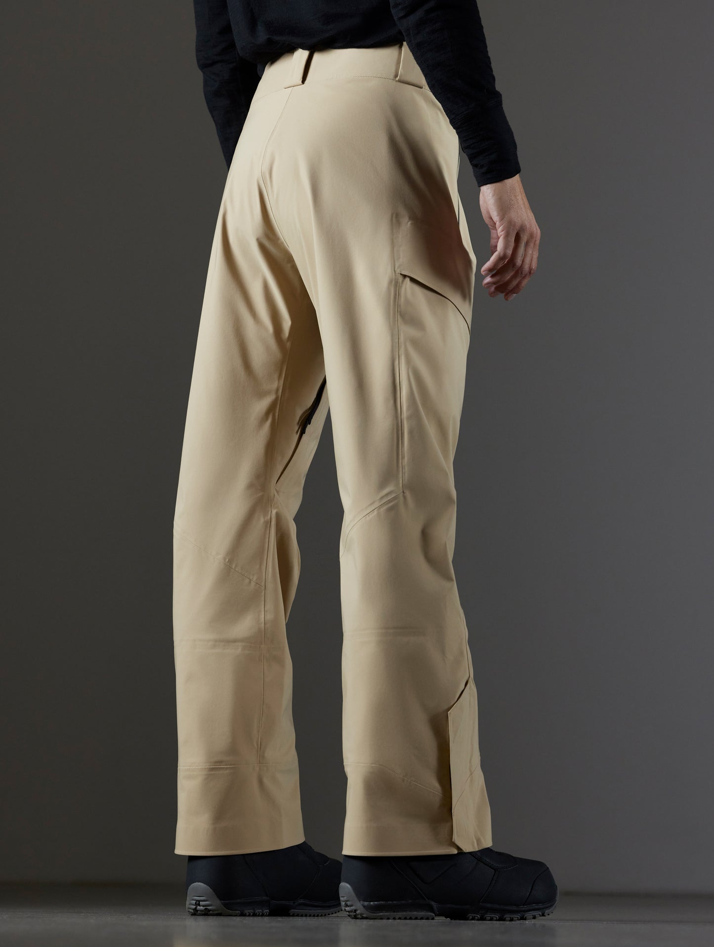 Rear 3/4 lower body view of man wearing Maverick Snow-Shell Pant in Desert Tan from AETHER Apparel.