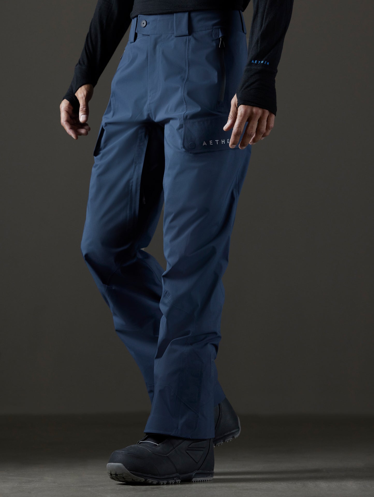 Front 3/4 lower body view of man wearing Maverick Snow-Shell Pant in Total Eclipse dark blue from AETHER Apparel.