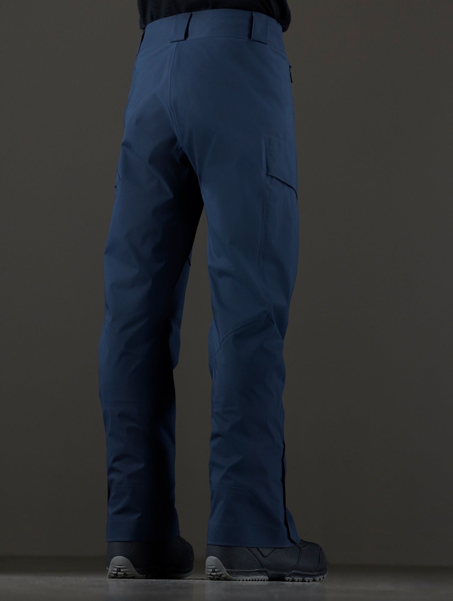 Rear 3/4 lower body view of man wearing Maverick Snow-Shell Pant in Total Eclipse dark blue from AETHER Apparel.