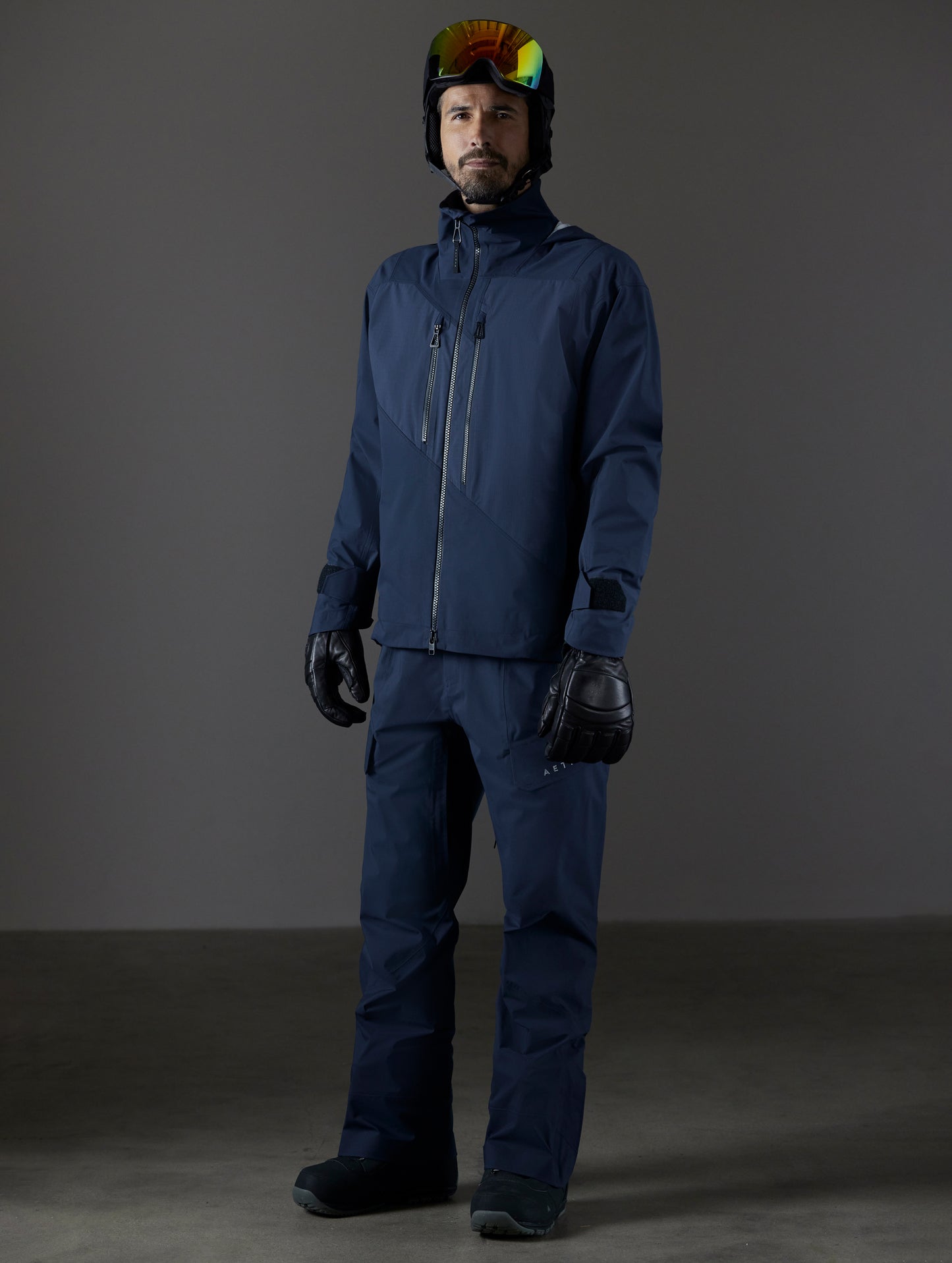 Front 3/4 full-body view of man wearing Maverick Snow-Shell Jacket and Maverick Snow-Shell Pant in Total Eclipse dark blue from AETHER Apparel.