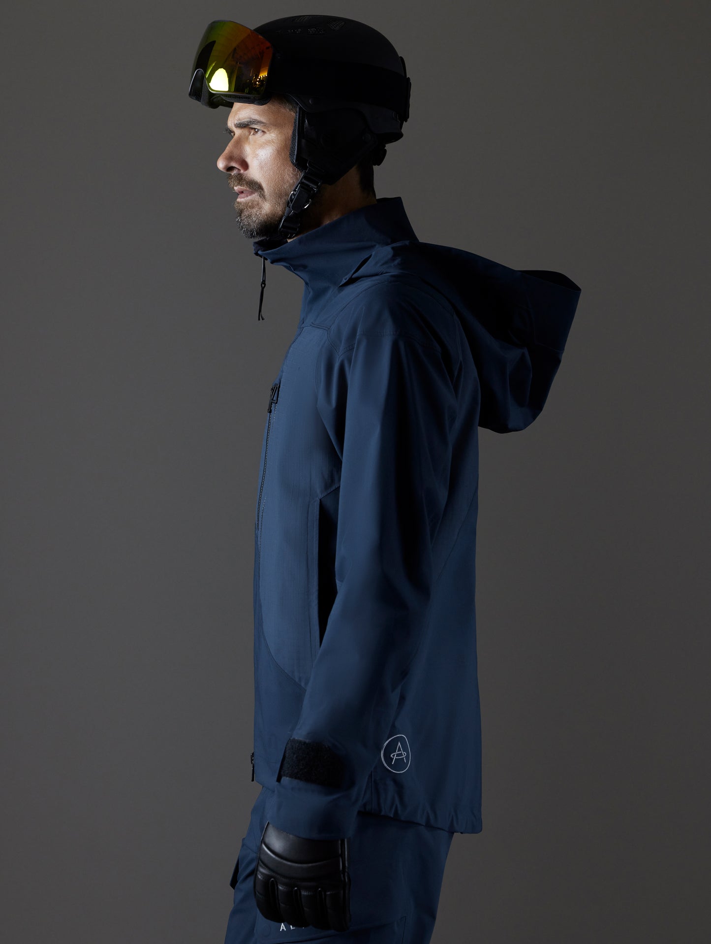 Side profile body view of man wearing Maverick Snow-Shell Jacket in Total Eclipse dark blue from AETHER Apparel.