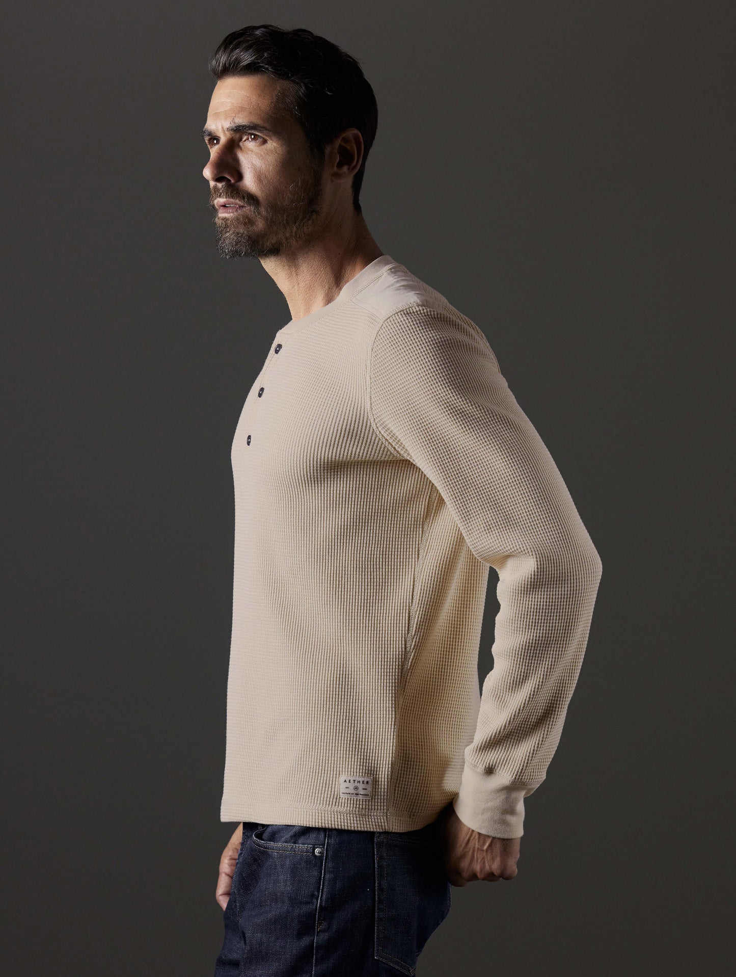 Side profile body view of man wearing Milford Waffle Henley in Bone white from AETHER Apparel.