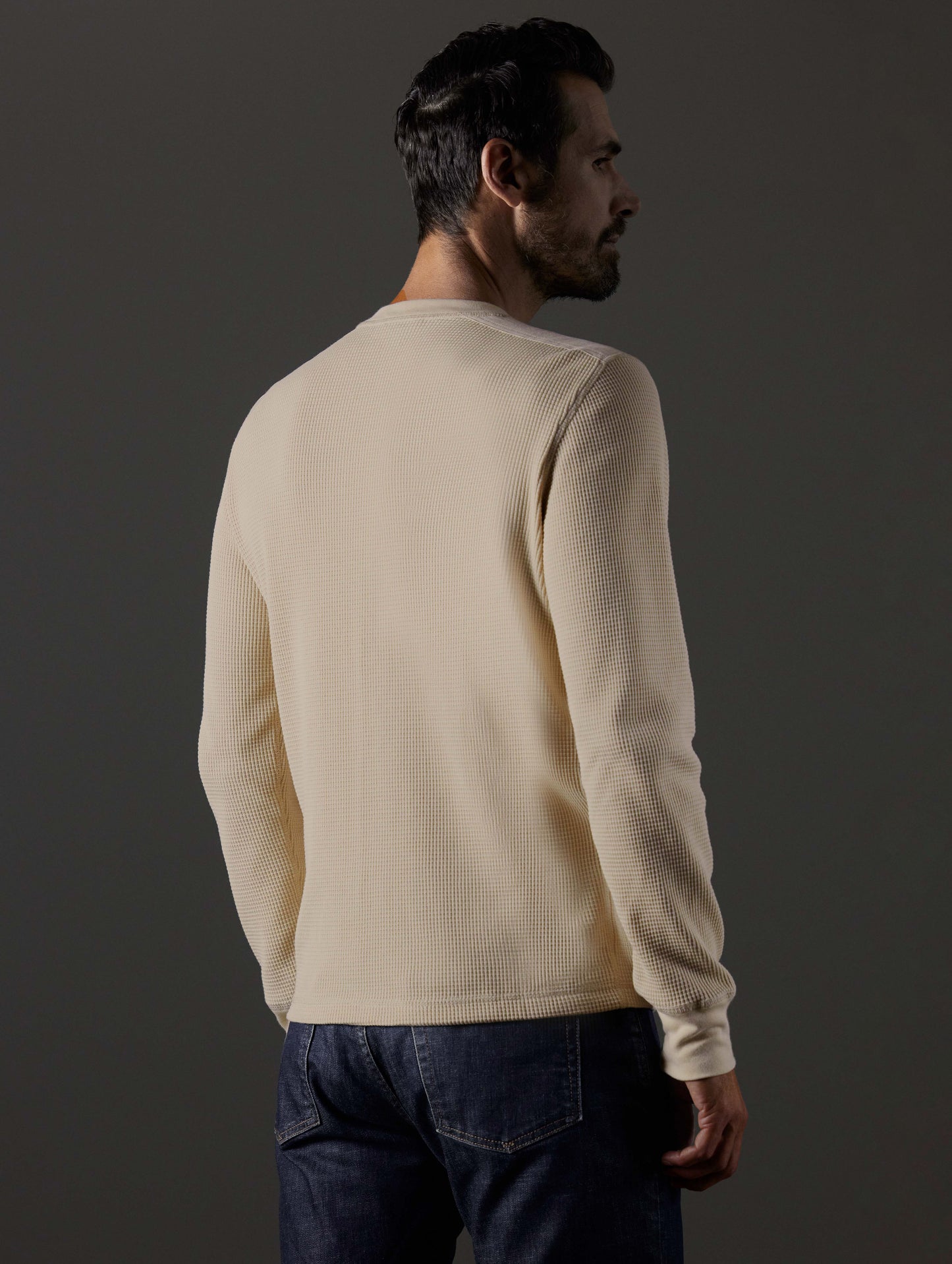 Rear 3/4 body view of man wearing Milford Waffle Henley in Bone white from AETHER Apparel.
