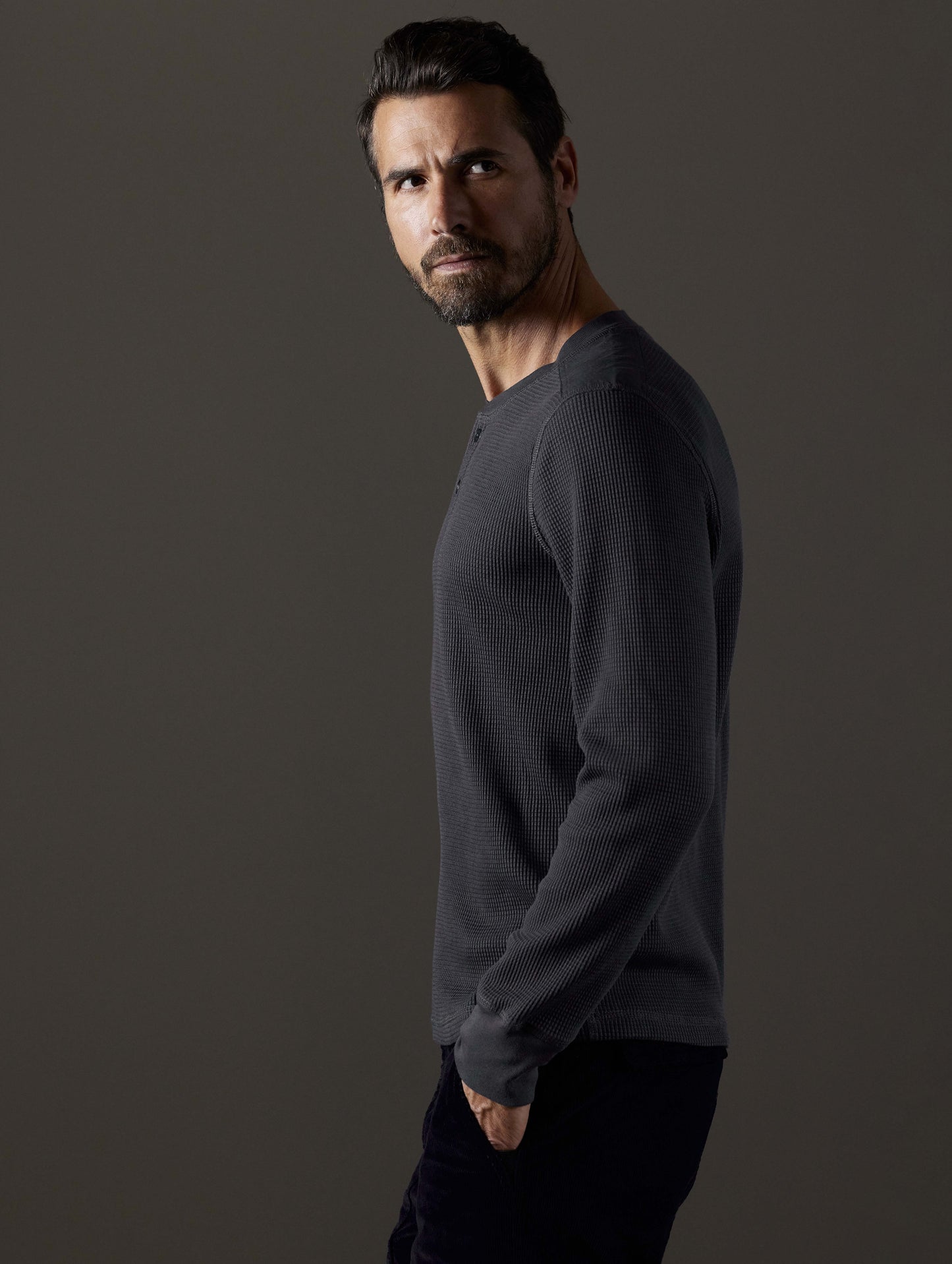 Side profile body view of man wearing Milford Waffle Henley in Graphite from AETHER Apparel.