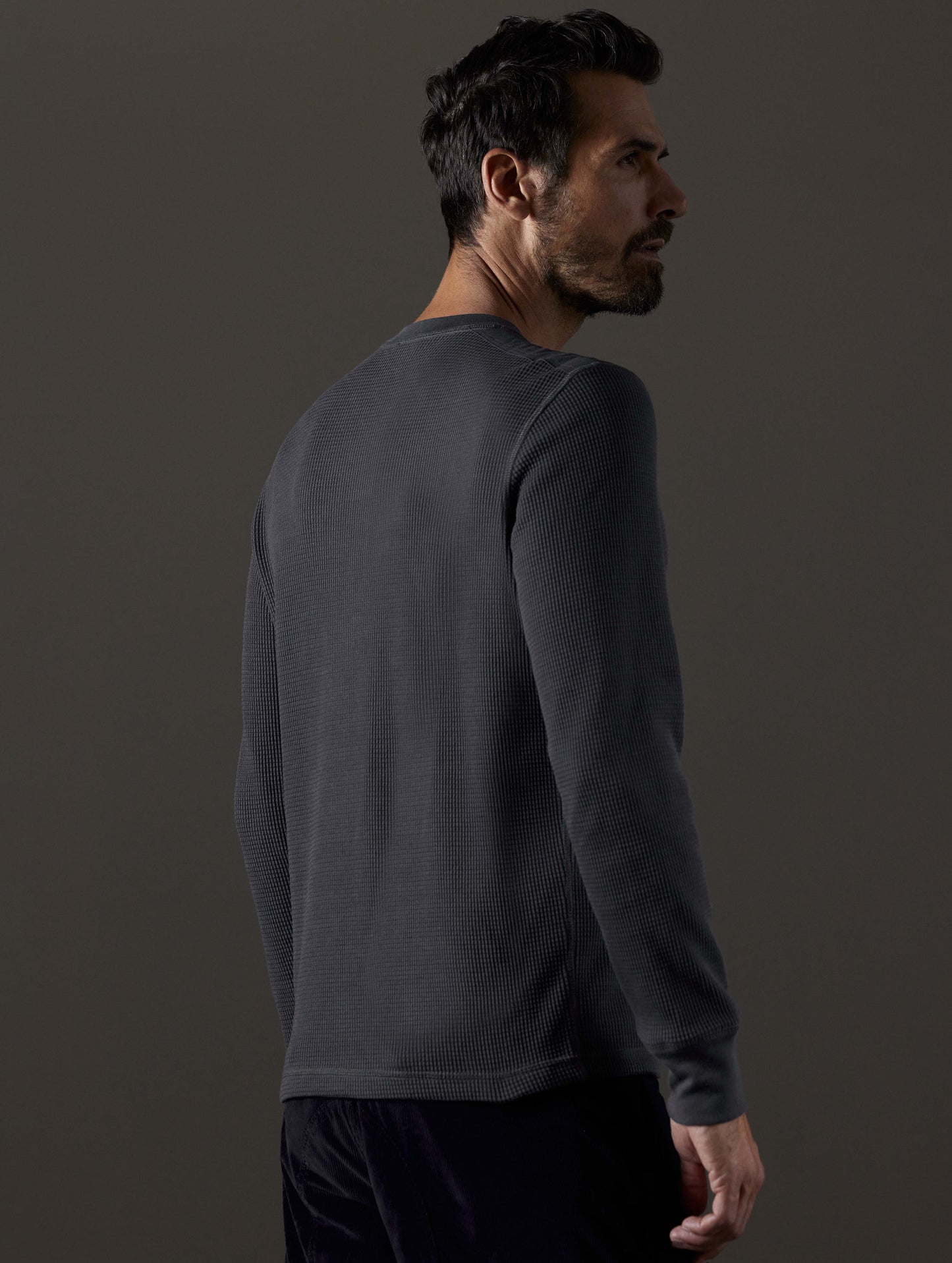 Rear 3/4 body view of man wearing Milford Waffle Henley in Graphite from AETHER Apparel.