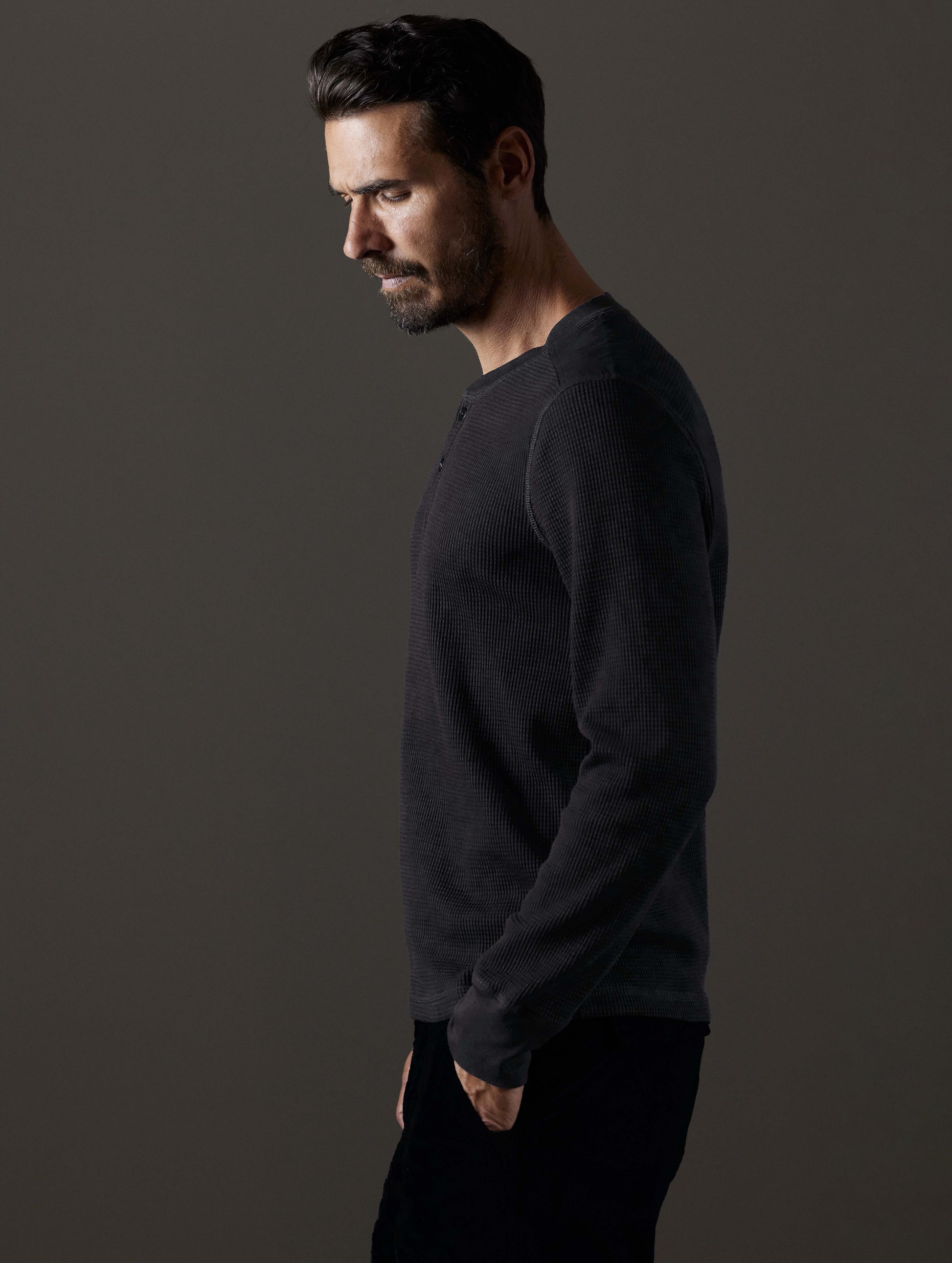Side profile body view of man wearing Milford Waffle Henley in Onyx Black from AETHER Apparel.