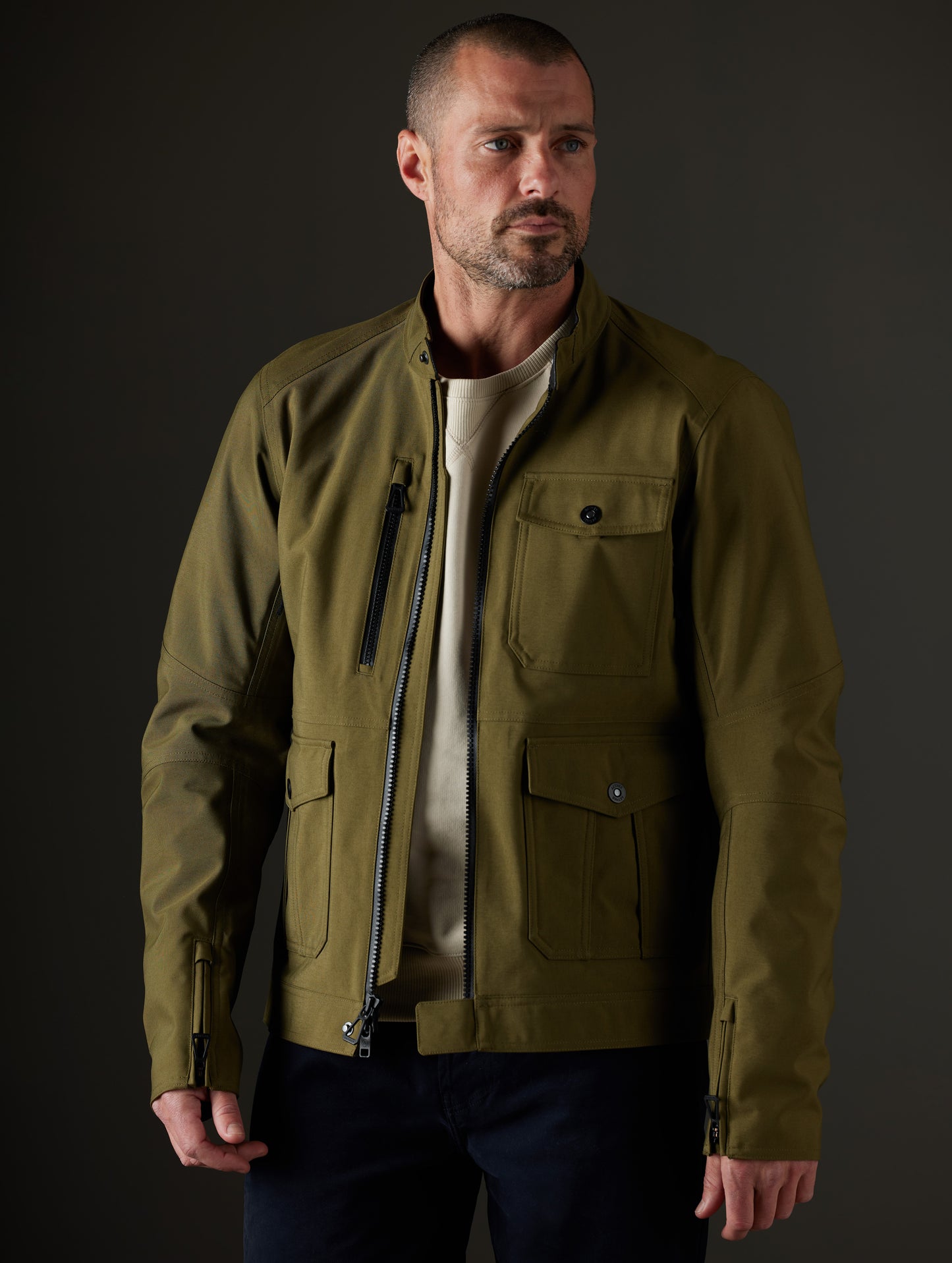 Front 3/4 body view of man wearing unzipped Mulholland Motorcycle Jacket in Command Green from AETHER Apparel.