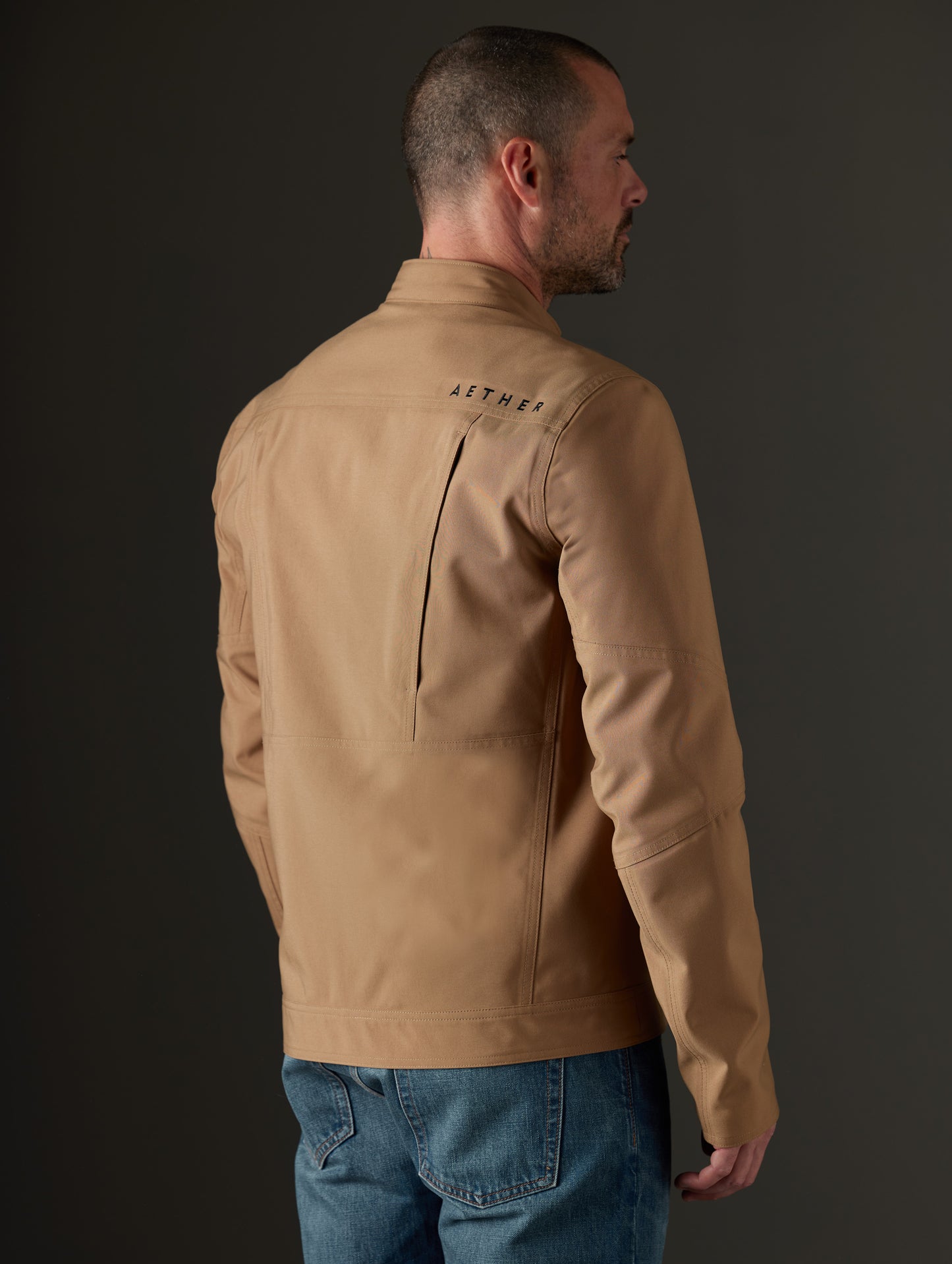 Rear 3/4 body view of man wearing Mulholland Motorcycle Jacket in Reverse Brown from AETHER Apparel.