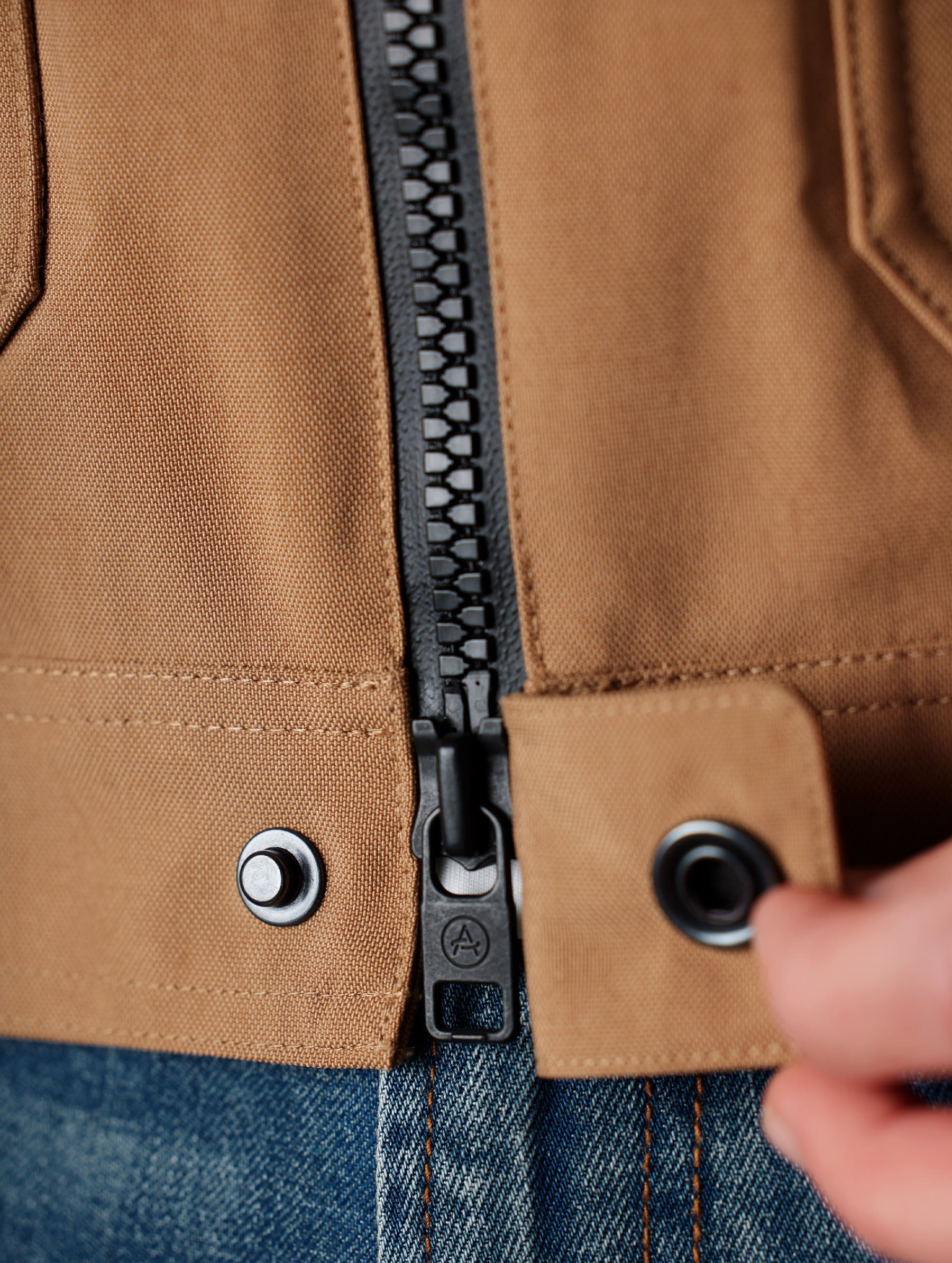 Closeup detailed view of the snap-secured, scratch-preventing hardware cover on the Mulholland Motorcycle Jacket in Reserve Brown from AETHER Apparel.