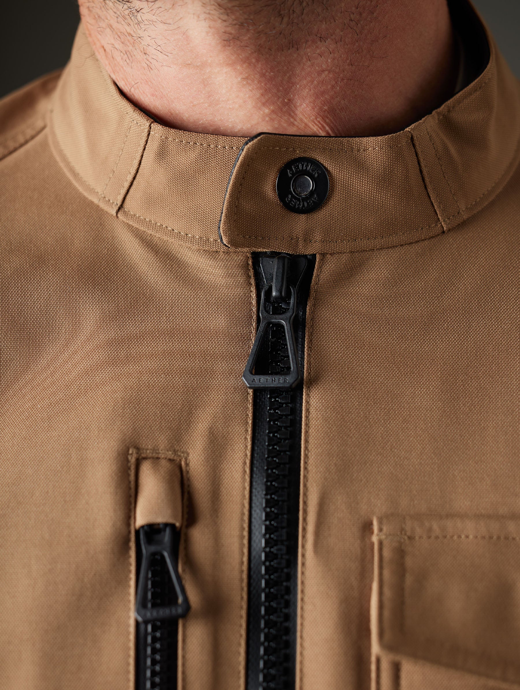 Closeup detailed view of the snap-secured collar and main center-front zipper on the Mulholland Motorcycle Jacket in Reserve Brown from AETHER Apparel.