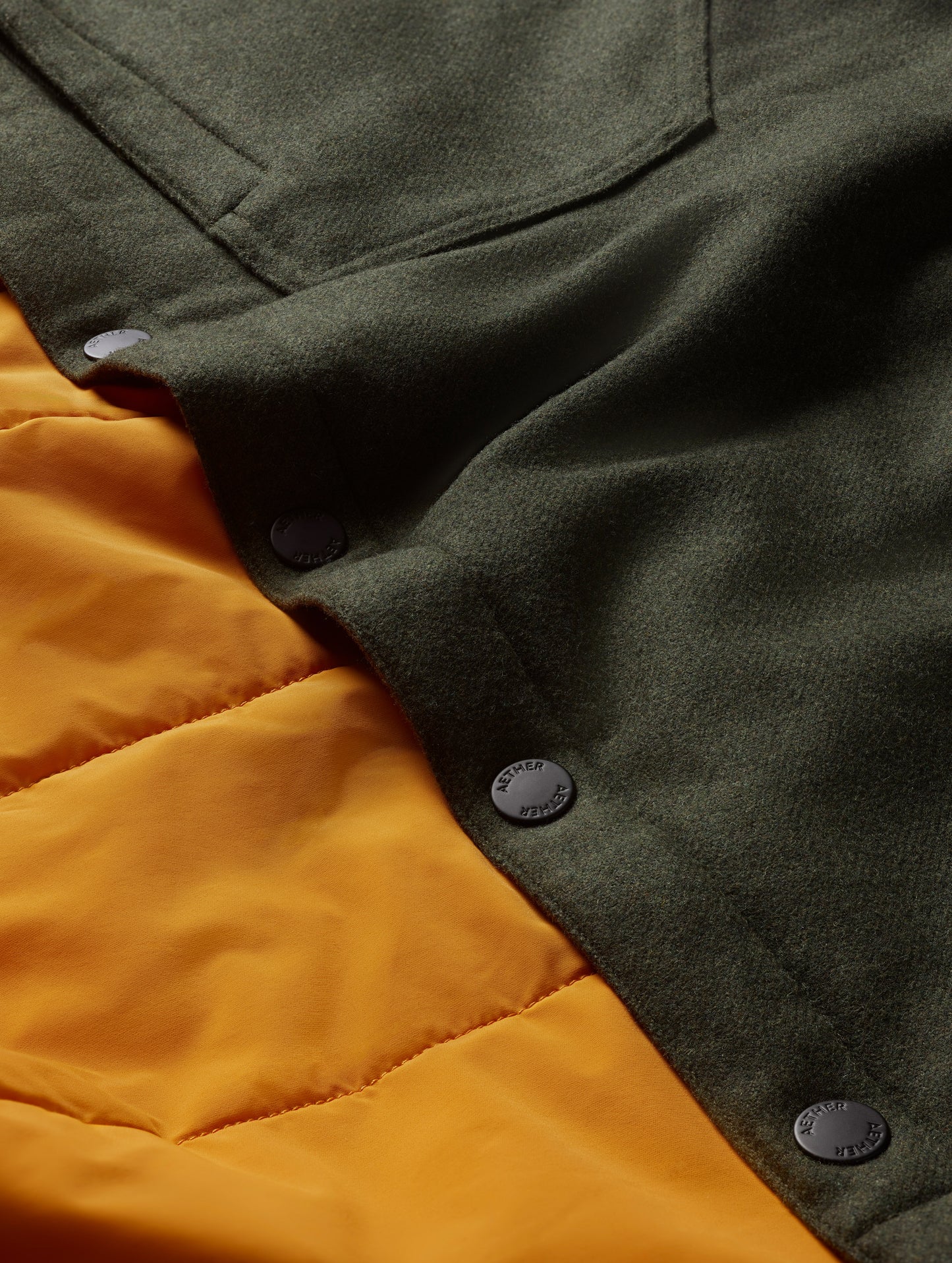 Closeup detailed view of buttons and orange liner on Nova Insulated Button-Down in Command Green from AETHER Apparel.