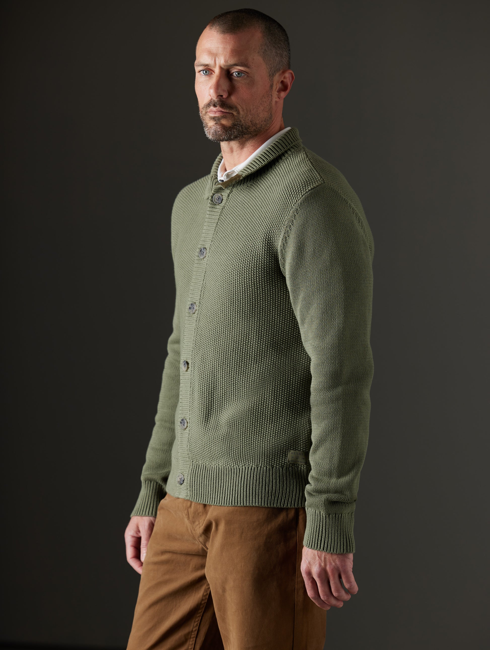 Side profile body view of man wearing Oliver Cotton Button-Up Sweater in Fern Green from AETHER Apparel.