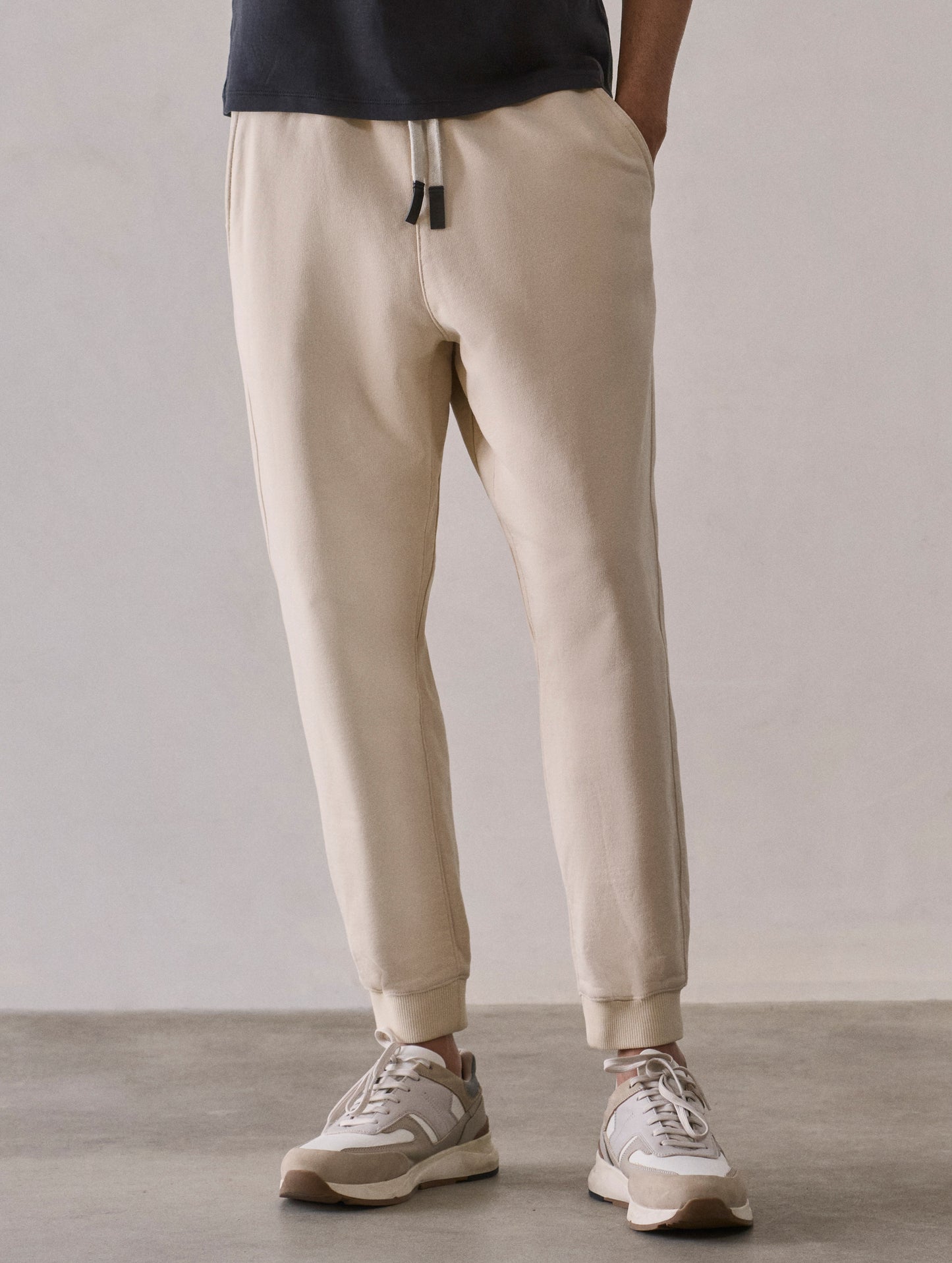 Front lower body view of man wearing Osa Cuffed Sweatpant in Bone white from AETHER Apparel.