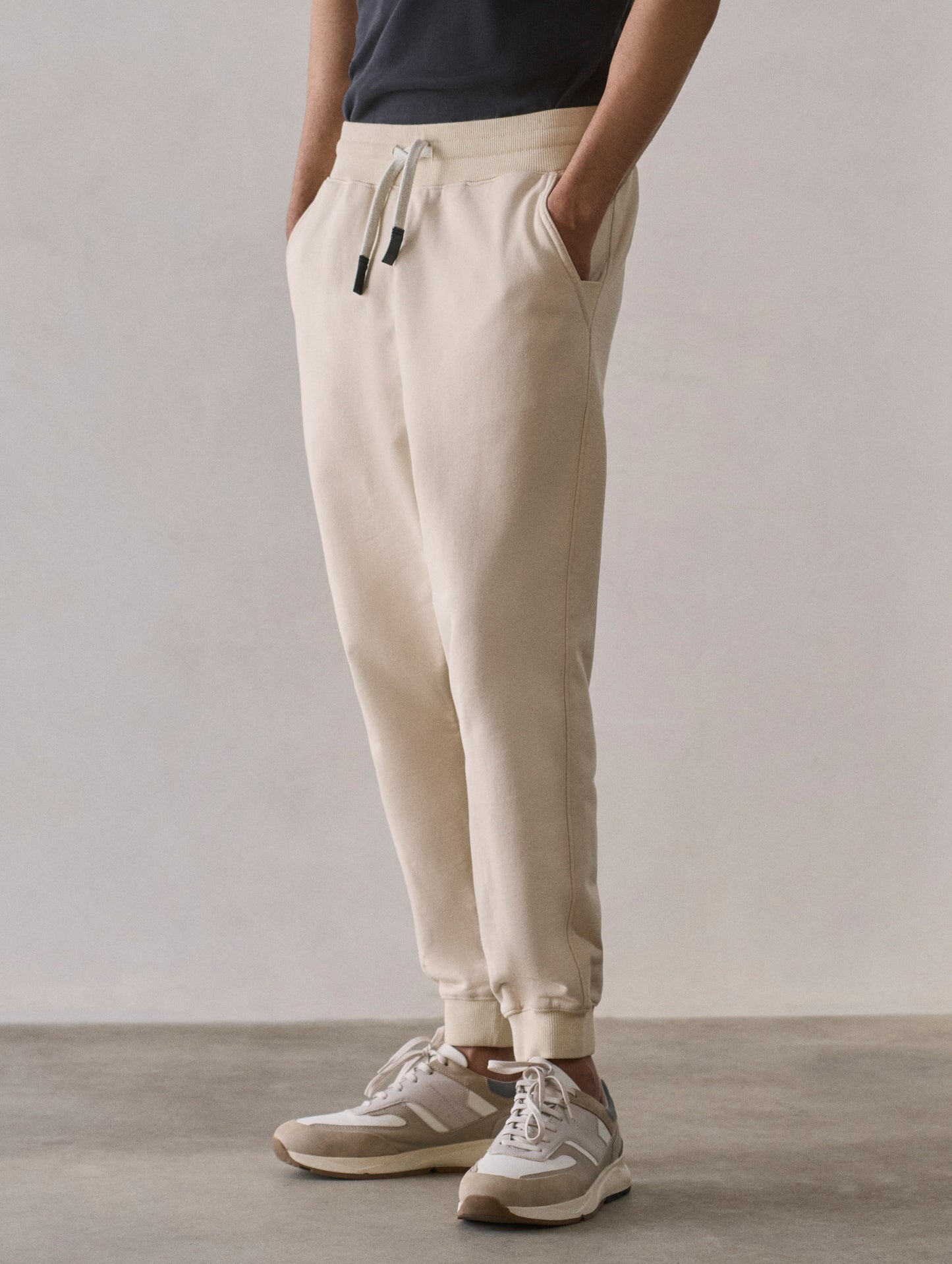 Front 3/4 lower body view of man wearing Osa Cuffed Sweatpant in Bone white from AETHER Apparel.