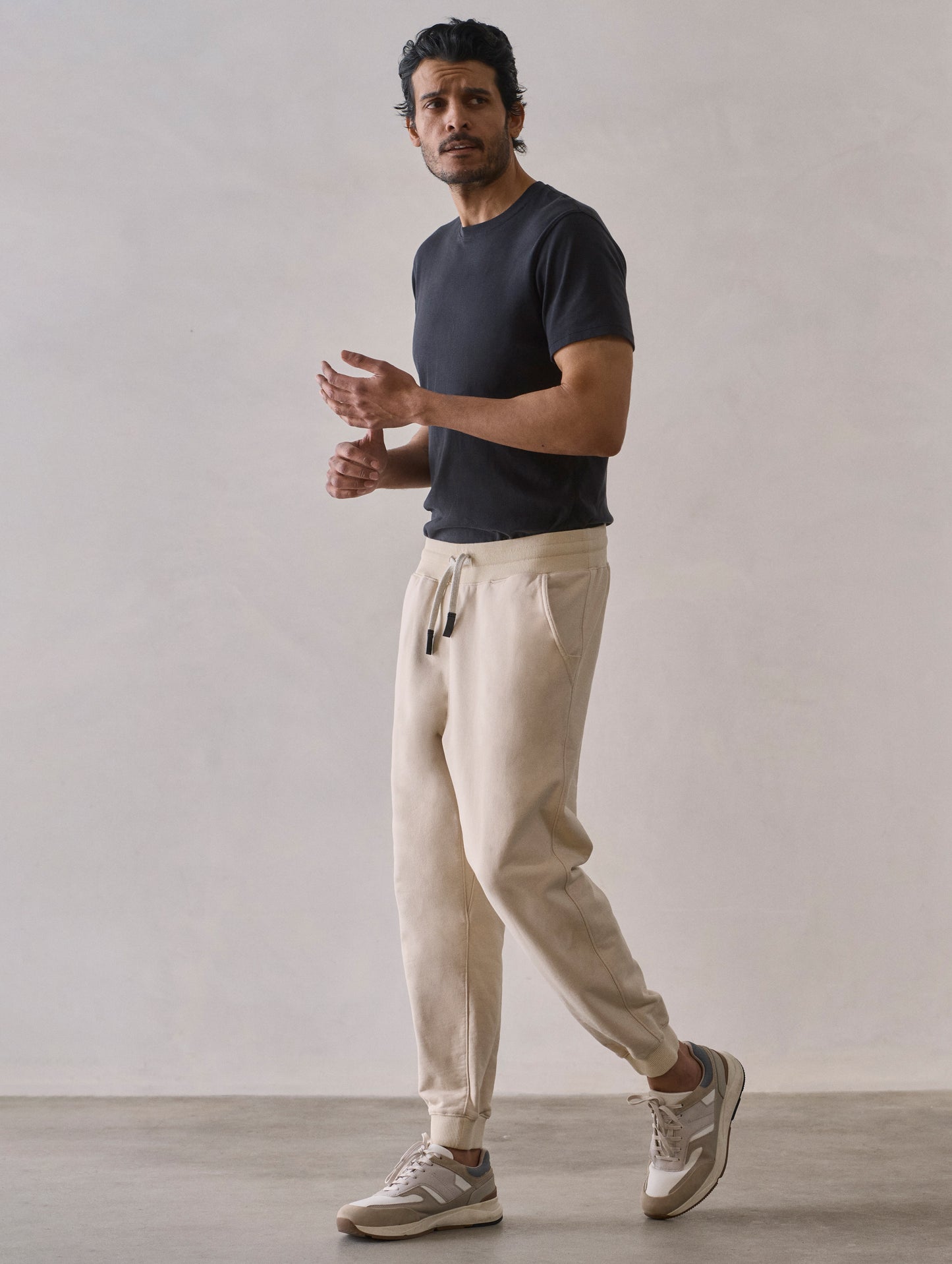 Front 3/4 full-body view of man wearing Osa Cuffed Sweatpant in Bone white from AETHER Apparel.