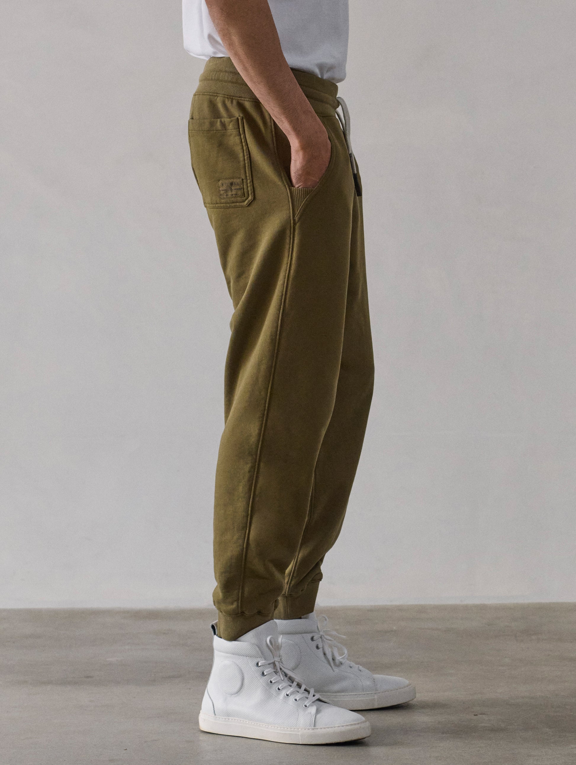 Right side profile lower-body view of man wearing Osa Cuffed Sweatpant in Command Green from AETHER Apparel.