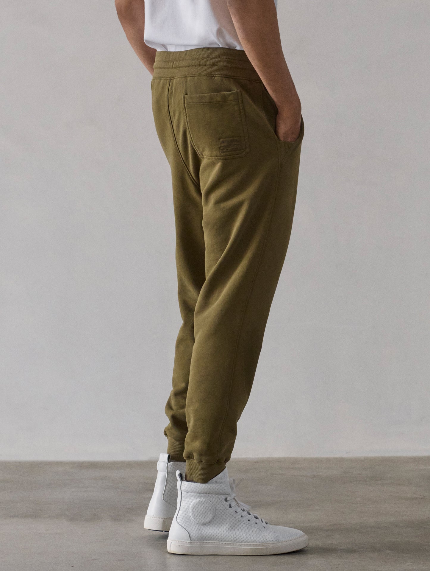 Rear 3/4 lower-body view of man wearing Osa Cuffed Sweatpant in Command Green from AETHER Apparel.