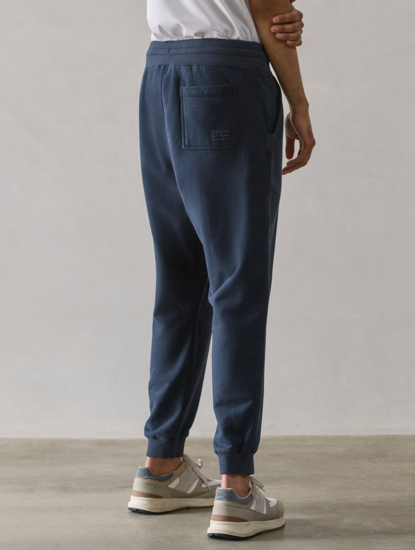 Rear 3/4 lower body view of man wearing Osa Cuffed Sweatpant in Total Eclipse dark blue from AETHER Apparel.
