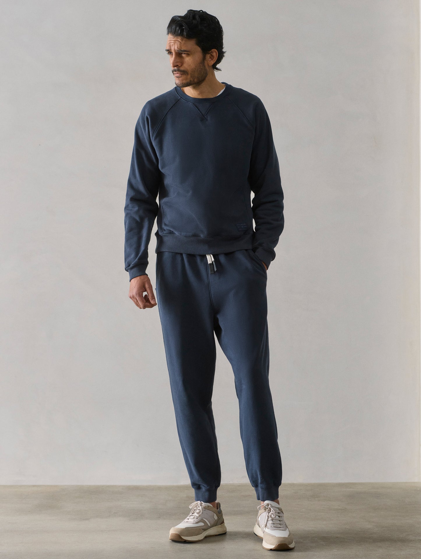Front full-body view of man wearing Osa Cuffed Sweatpant in Total Eclipse dark blue from AETHER Apparel.