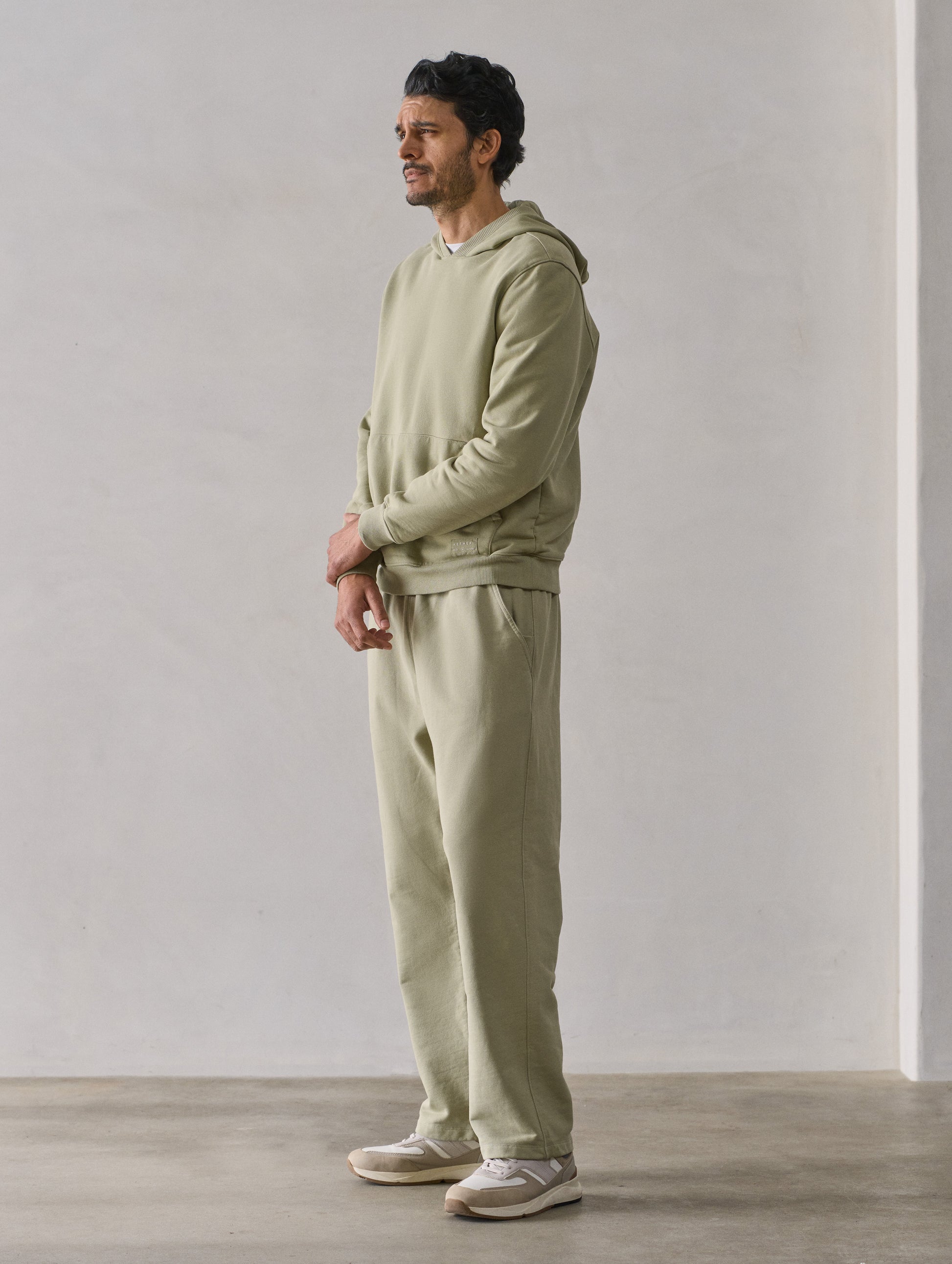 Front 3/4 full-body view of man wearing Osa Pullover Hoodie in Sage Green from AETHER Apparel.