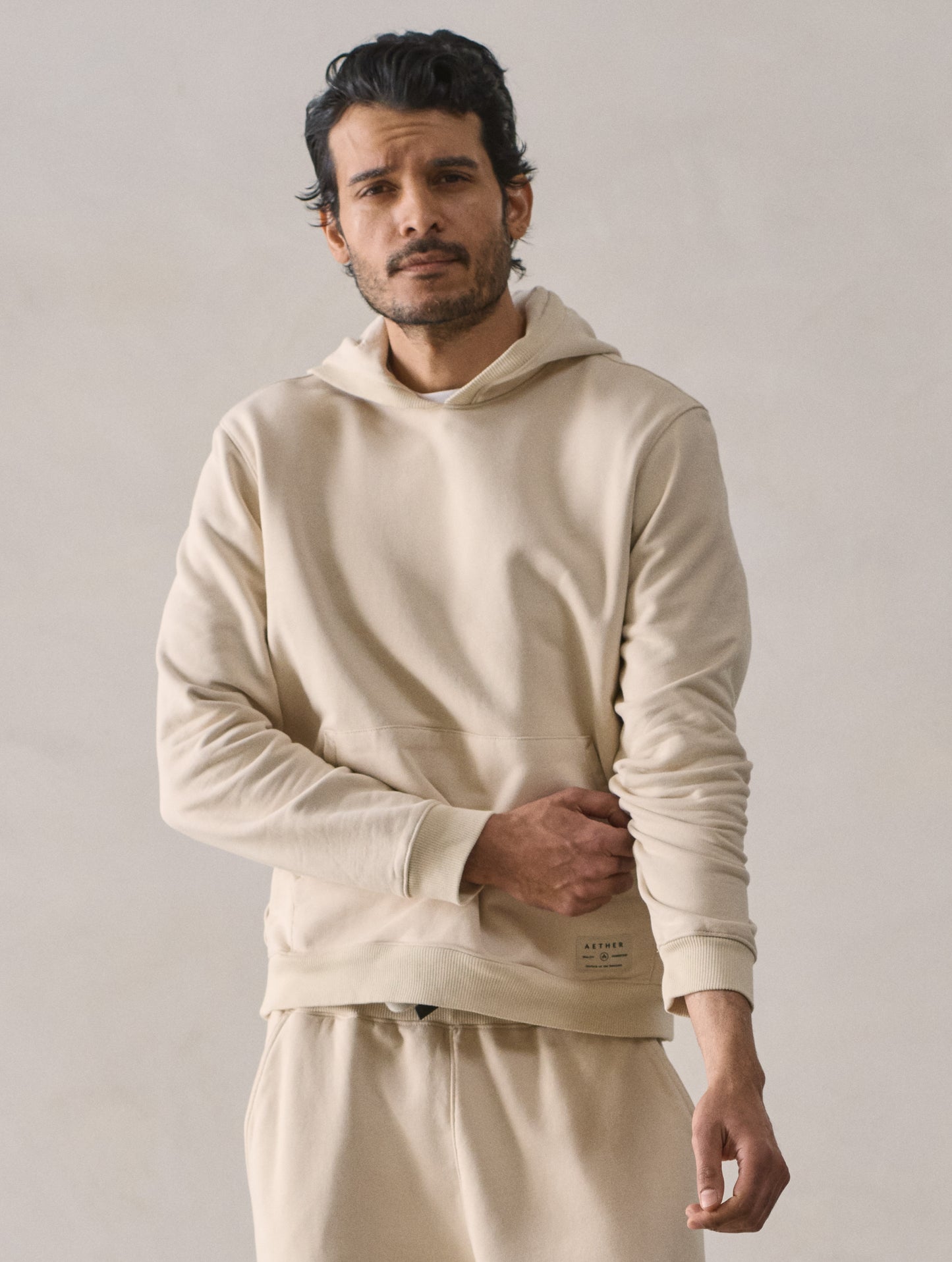 Front upper body view of man wearing Osa Pullover Hoodie in Bone white from AETHER Apparel.