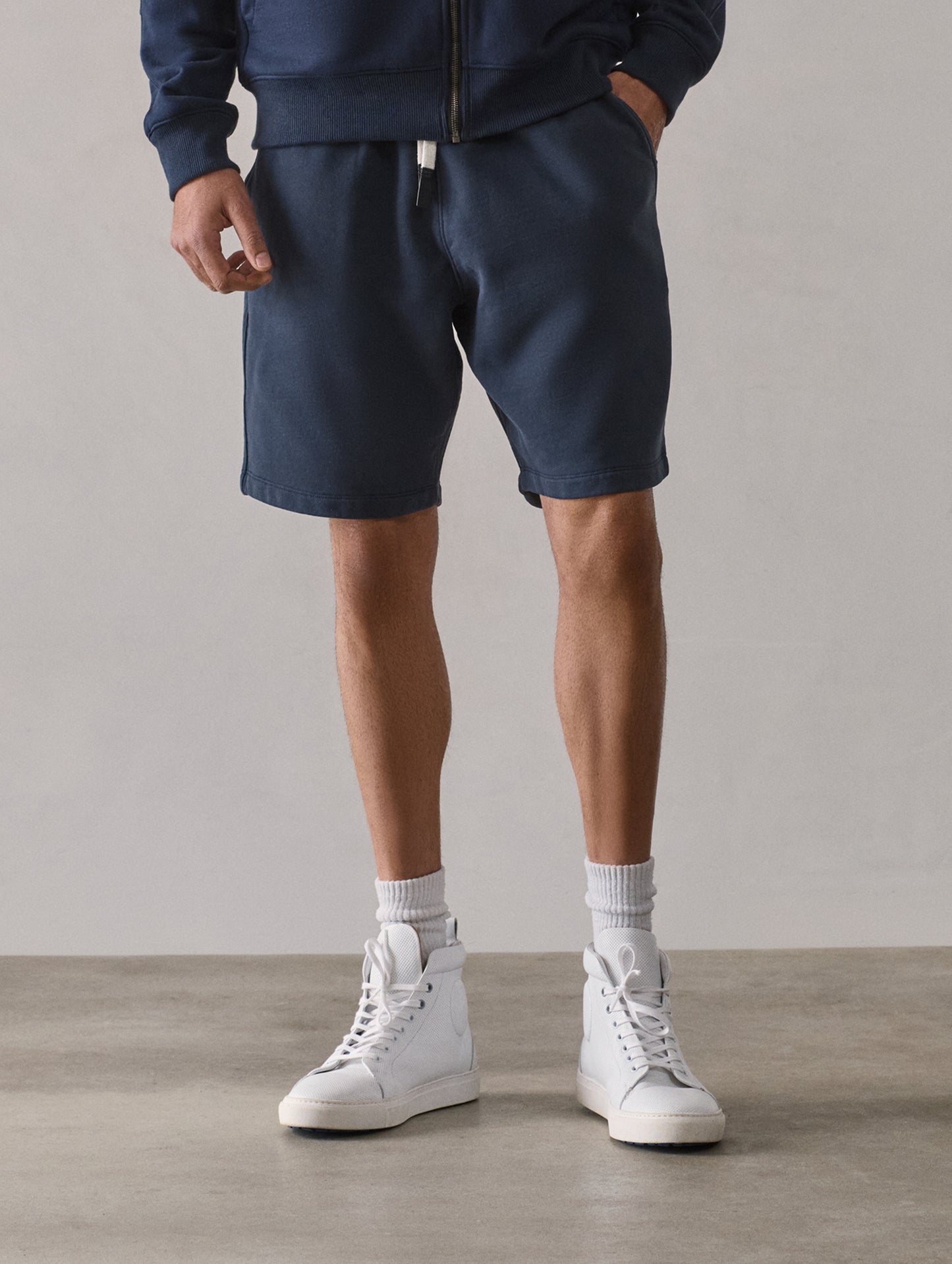 Front lower-body view of man wearing Osa Sweatshort in Total Eclipse dark blue from AETHER Apparel.